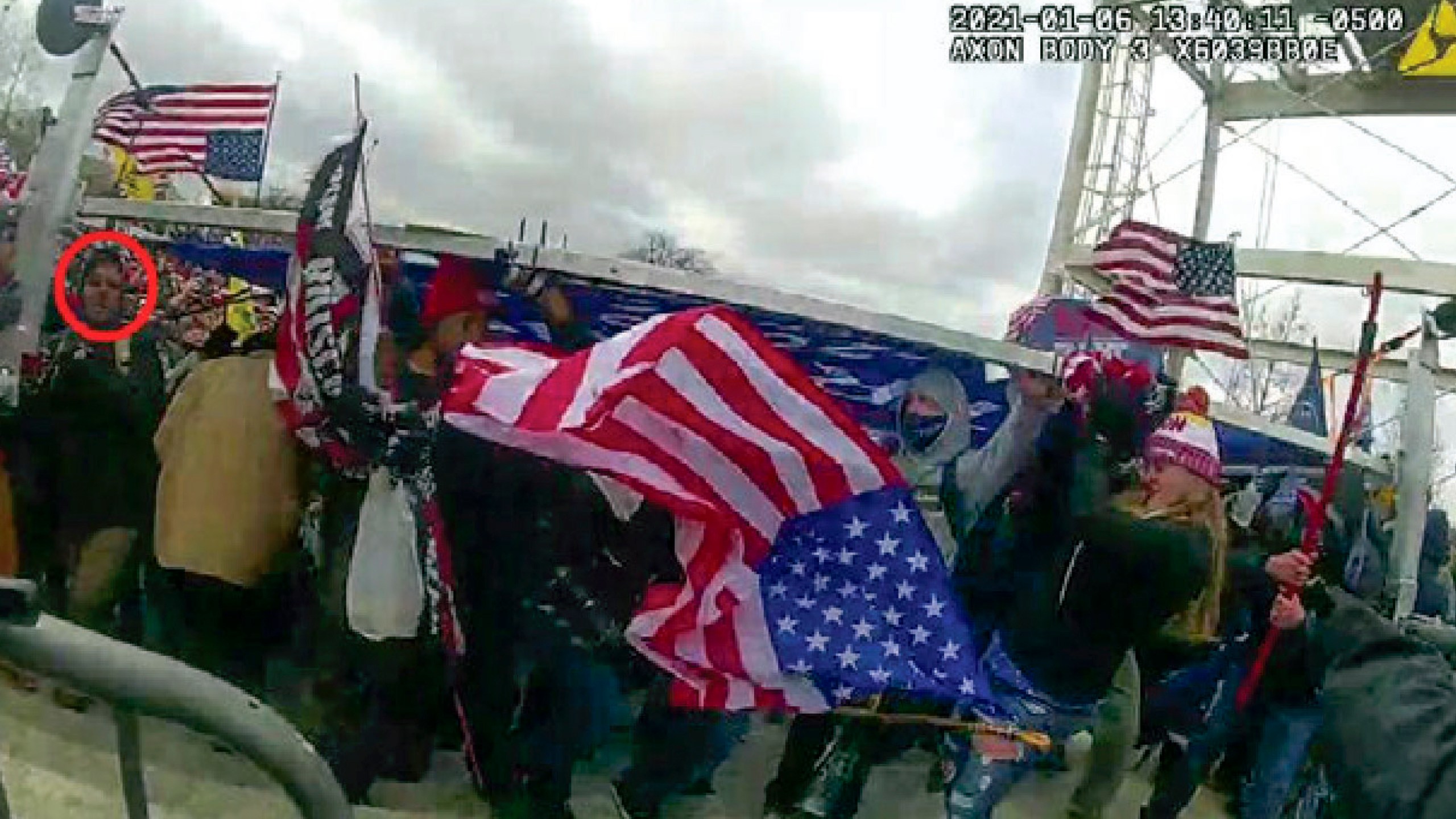 This image from a police-worn body camera and provided and annotated by the Justice Department shows Jeffrey Newcomb, 41, of Polk, Ohio, circled in red, on the East Front of the U.S. Capitol, Jan. 6, 2021, in Washington. Newcomb was arrested Oct. 22, 2024, on charges that he brought a massive "Trump" sign to the U.S. Capitol and joined other rioters in using it as a weapon against police officers during a mob attack. (Department of Justice via AP)