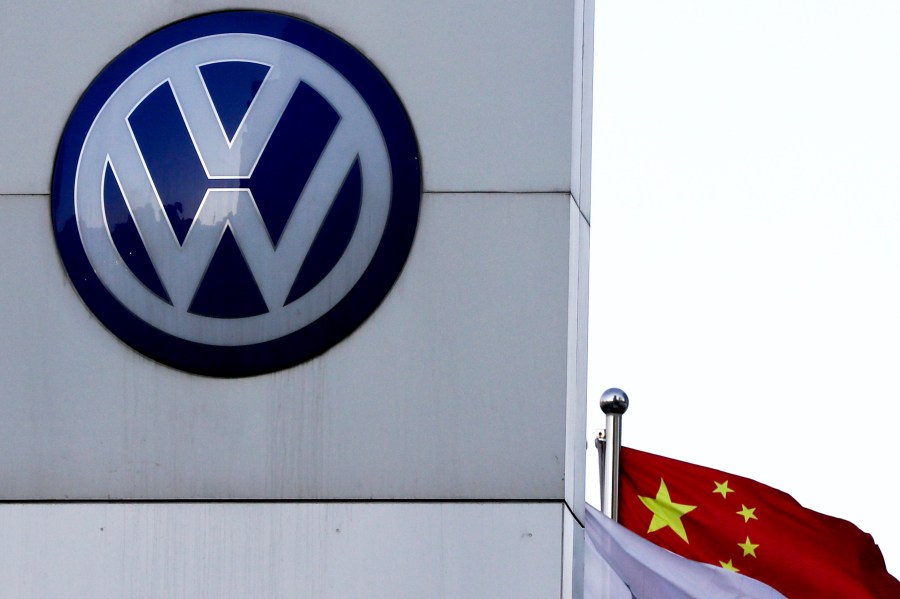 FILE - A Chinese national flag flutters near a Volkswagen logo in Beijing, Tuesday, April 18, 2017. (AP Photo/Andy Wong, File)