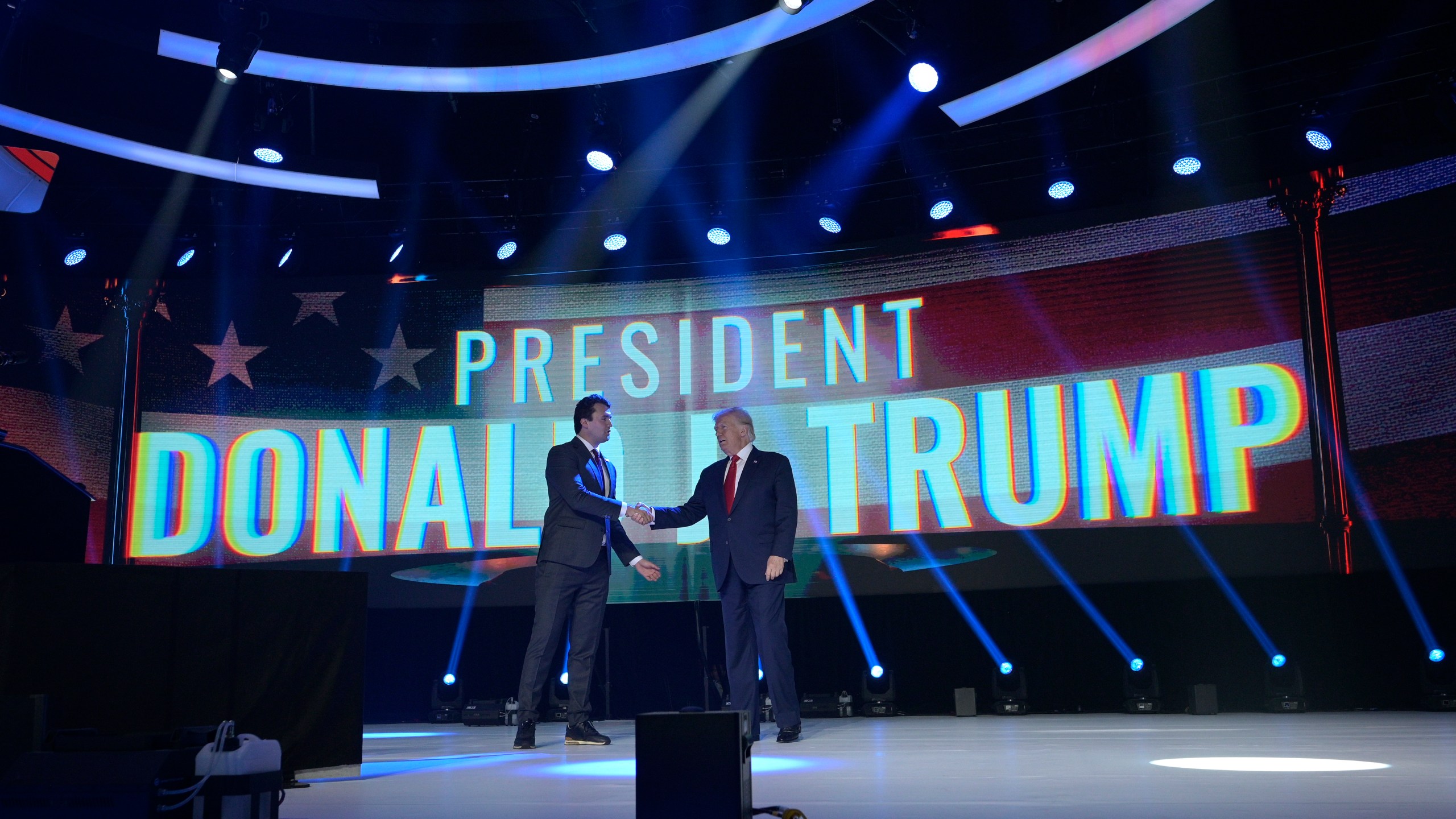 FILE - Former President Donald Trump, right, shakes hands with Turning Point CEO Charlie Kirk before speaking during the Turning Point USA Student Action Summit, Saturday, July 23, 2022, in Tampa, Fla. (AP Photo/Phelan M. Ebenhack, File)