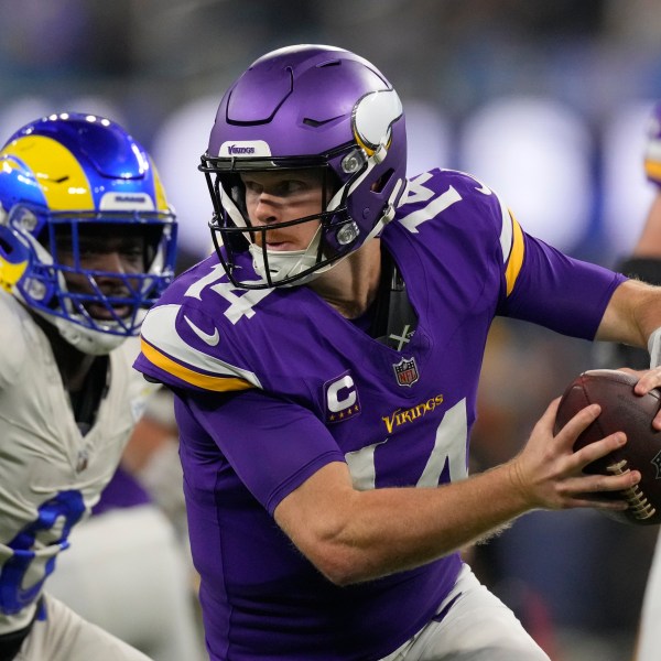 Minnesota Vikings quarterback Sam Darnold (14) scrambles while pressured by Los Angeles Rams linebacker Byron Young (0) during the first half of an NFL football game Thursday, Oct. 24, 2024, in Inglewood, Calif. (AP Photo/Mark J. Terrill)