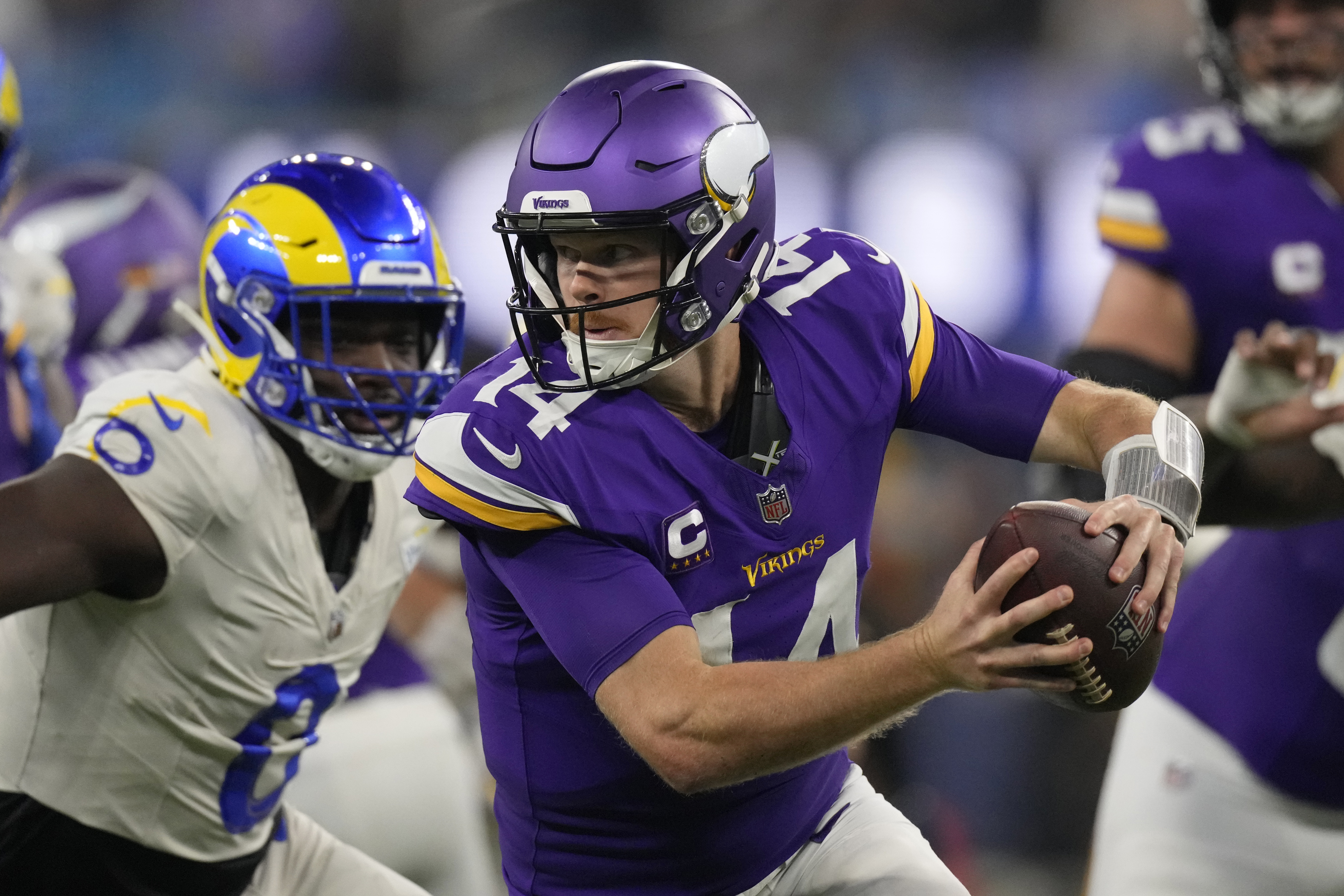 Minnesota Vikings quarterback Sam Darnold (14) scrambles while pressured by Los Angeles Rams linebacker Byron Young (0) during the first half of an NFL football game Thursday, Oct. 24, 2024, in Inglewood, Calif. (AP Photo/Mark J. Terrill)