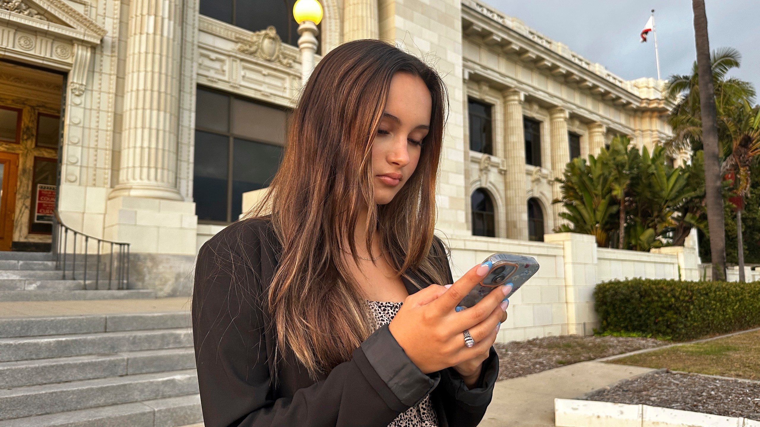 Kaylin Hayman, 17, scrolls on her phone outside Ventura City Hall in Ventura, Calif., Oct. 17, 2024. (AP Photo/Eugene Garcia)