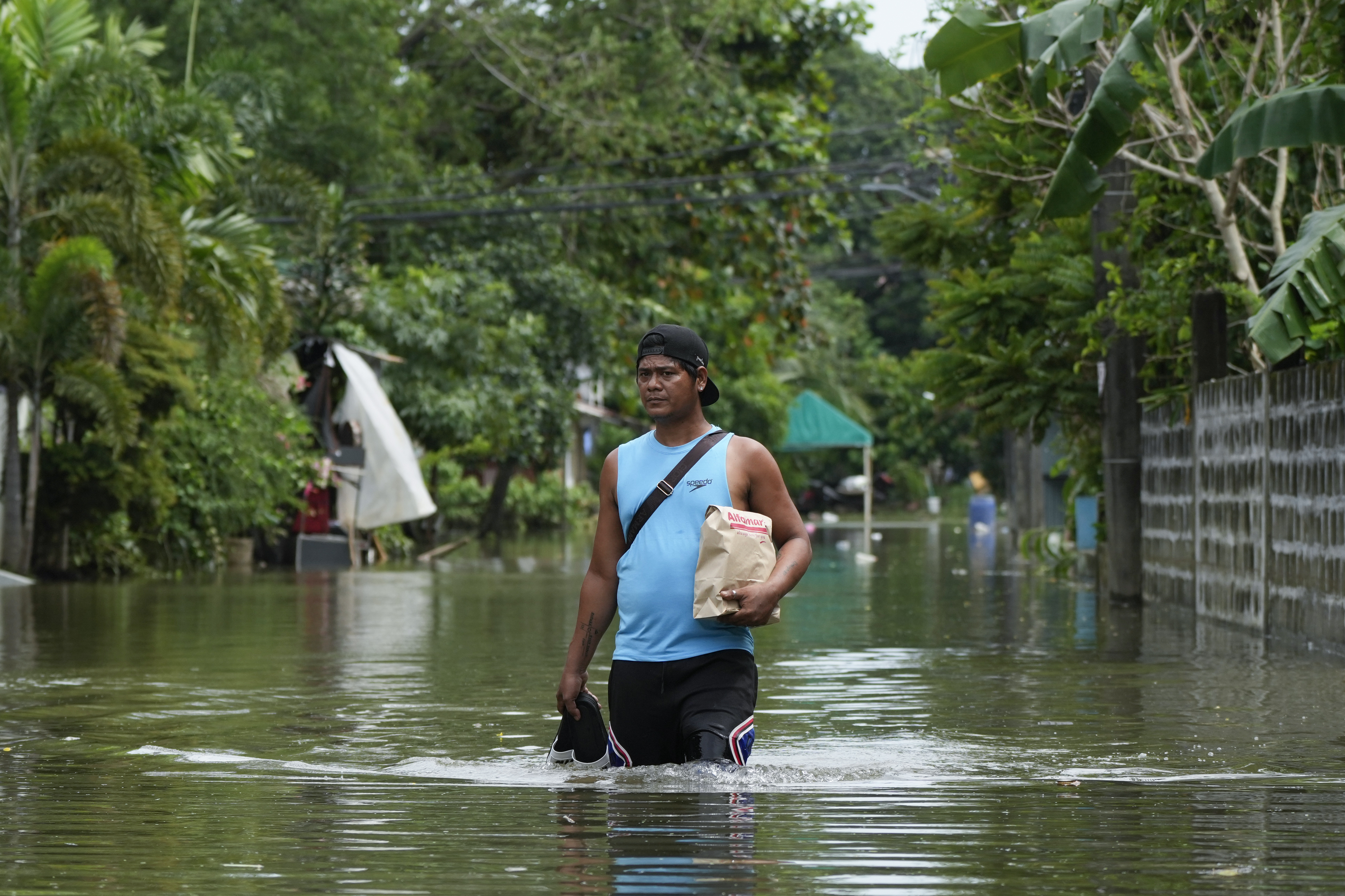 A resident navigates flooded streets caused by Tropical Storm Trami on Friday, Oct. 25, 2024, in Cainta, Rizal province, Philippines. (AP Photo/Aaron Favila)