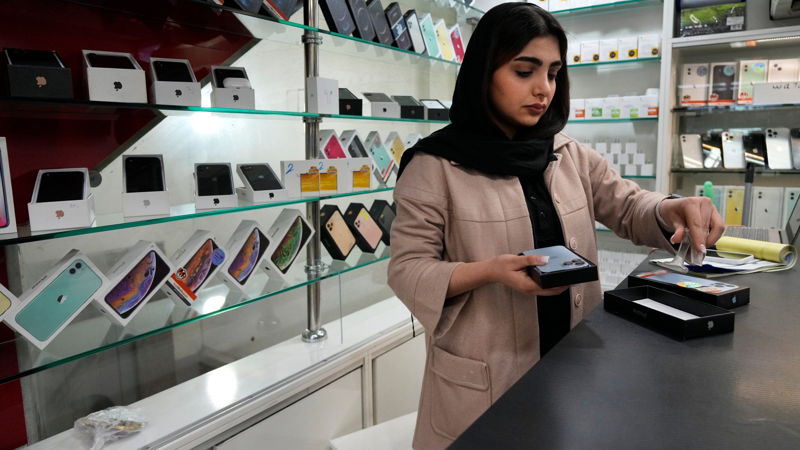 FILE - A cellphone vendor works at her shop in downtown Tehran, Iran, Wednesday, Feb. 21, 2024. (AP Photo/Vahid Salemi, File)