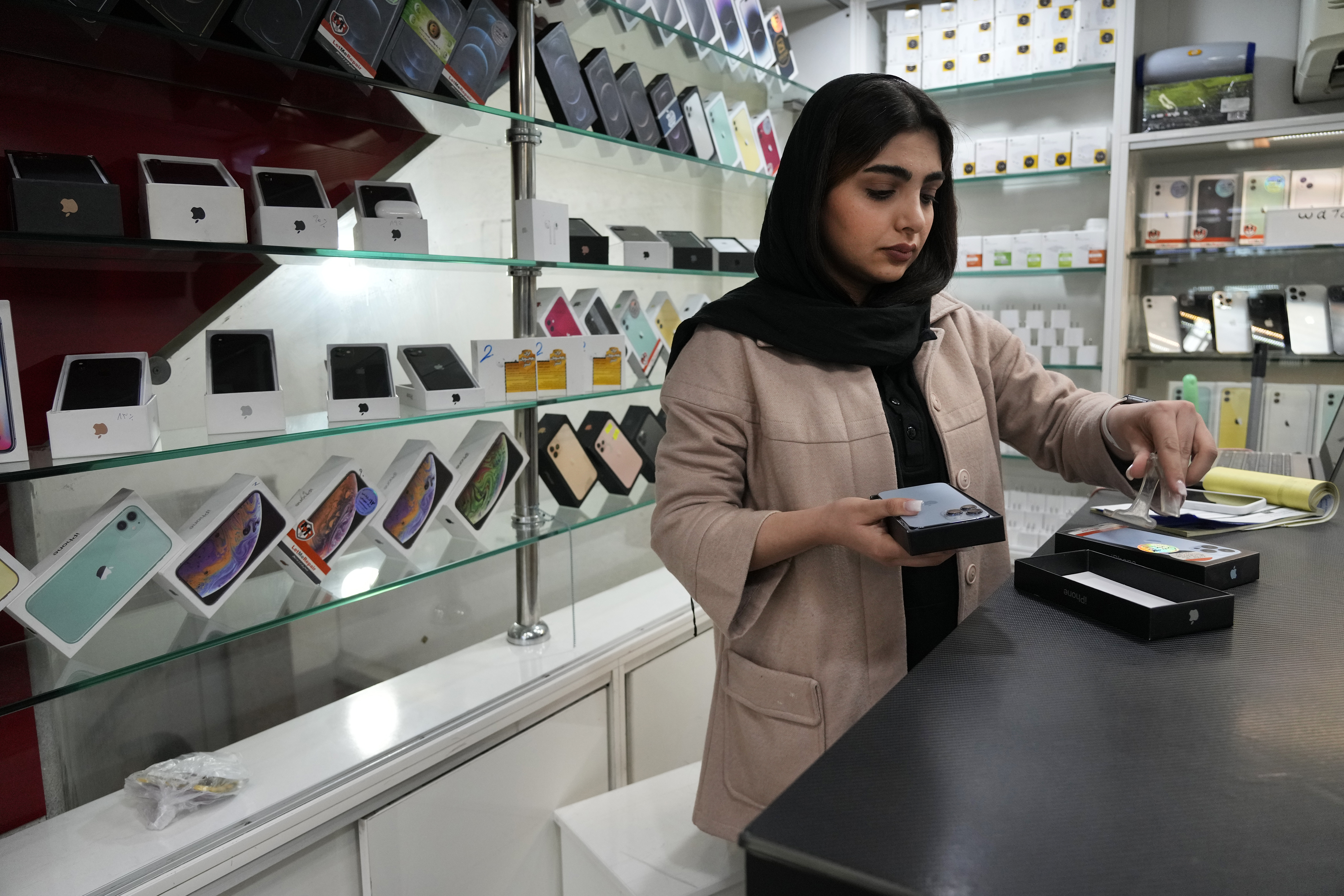 FILE - A cellphone vendor works at her shop in downtown Tehran, Iran, Wednesday, Feb. 21, 2024. (AP Photo/Vahid Salemi, File)