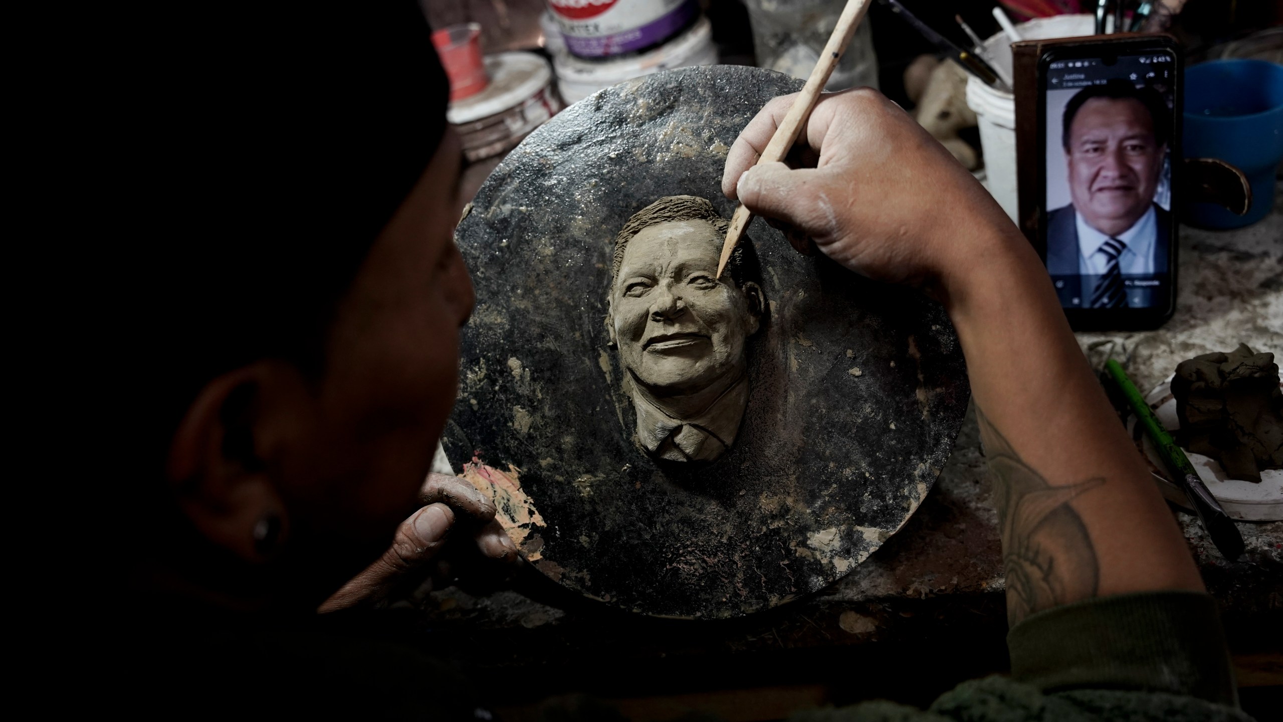 Artisan William Luna creates a mask of a loved one for the Mendoza family to adorn a piece of tantawawa, a sweet bread traditional for Day of the Dead celebrations, in La Paz, Bolivia, Thursday, Oct. 31, 2024. (AP Photo/Freddy Barragan)