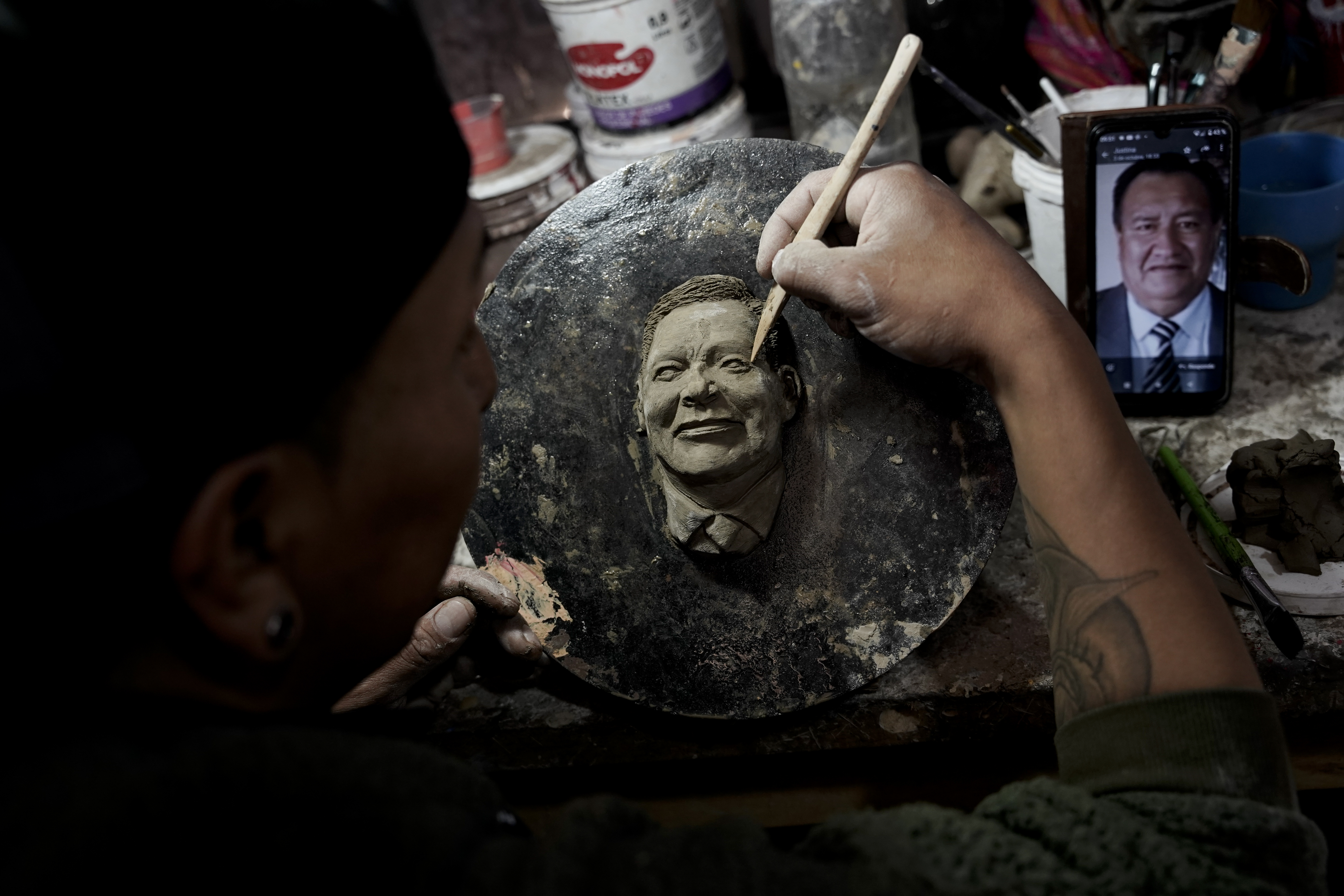 Artisan William Luna creates a mask of a loved one for the Mendoza family to adorn a piece of tantawawa, a sweet bread traditional for Day of the Dead celebrations, in La Paz, Bolivia, Thursday, Oct. 31, 2024. (AP Photo/Freddy Barragan)