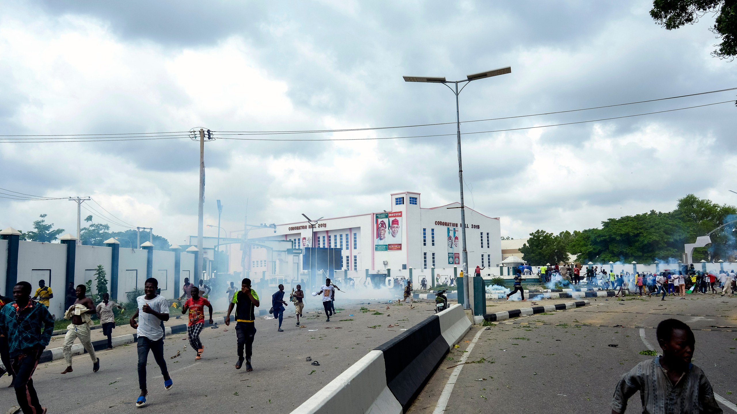 FILE - People run away from tear gas during a protest on the street in Kano, Nigeria, Aug. 1, 2024. (AP Photo/Sani Maikatanga, File)