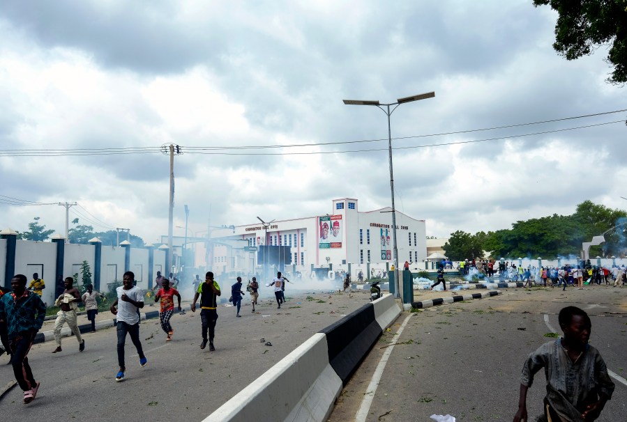 FILE - People run away from tear gas during a protest on the street in Kano, Nigeria, Aug. 1, 2024. (AP Photo/Sani Maikatanga, File)