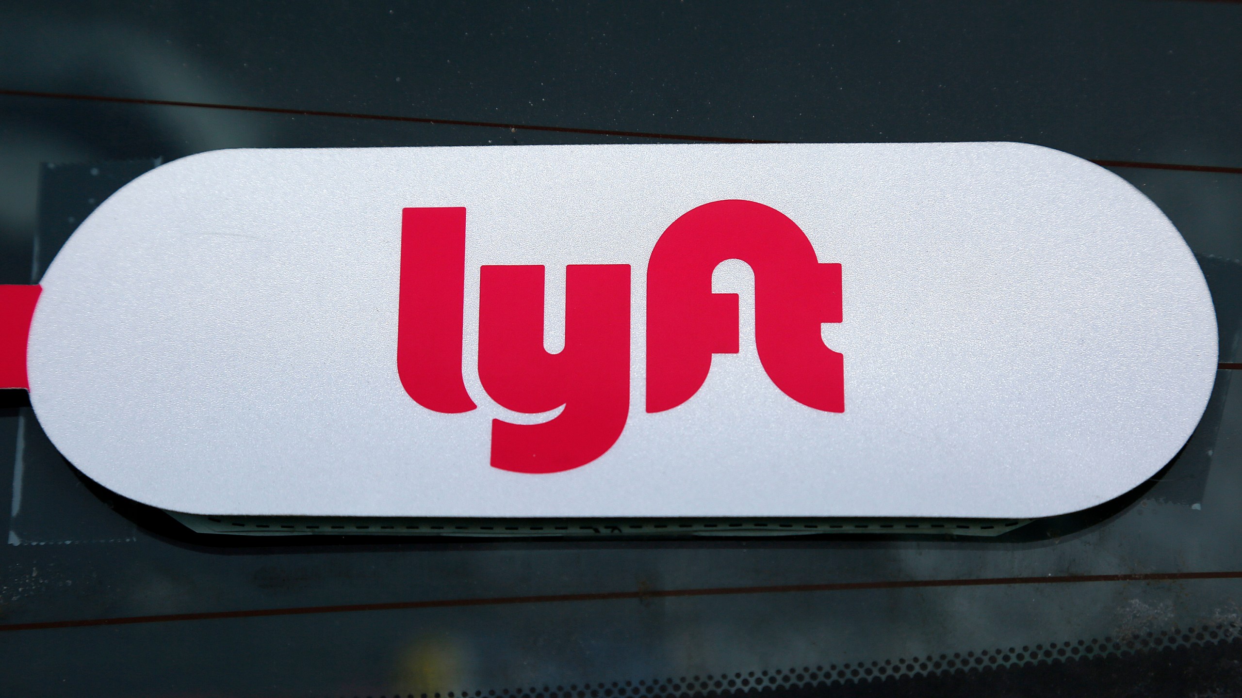 FILE - A Lyft logo is seen on a Lyft driver's car in Pittsburgh, Jan. 31, 2018. (AP Photo/Gene J. Puskar, File)