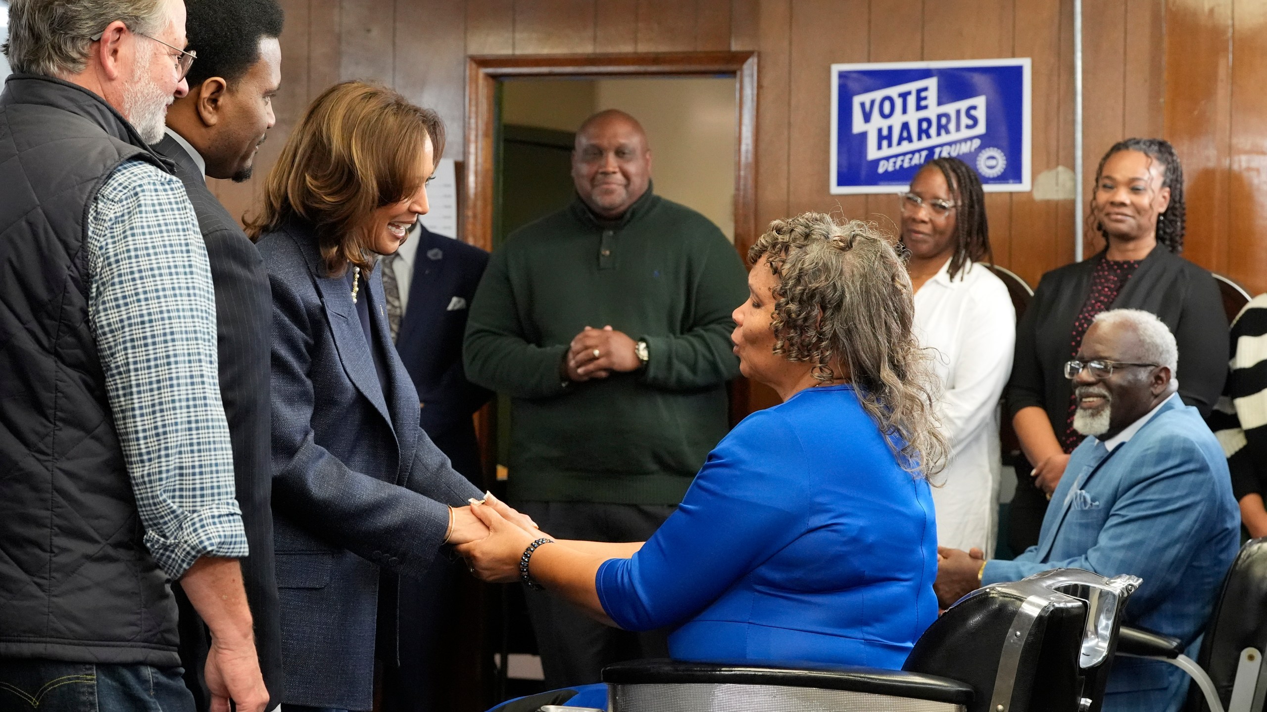 Democratic presidential nominee Vice President Kamala Harris, third left, greets Martha Roland, seated center right, and Roland Elam Sr., seated right, parents of Elam's barber shop owner Roland Elam Jr., second left, as Sen. Gary Peters, D-Mich., left, and others look on before participating in a roundtable discussion with local leaders at Elam's barber shop in Pontiac, Mich., Sunday, Nov. 3, 2024. (AP Photo/Jacquelyn Martin)