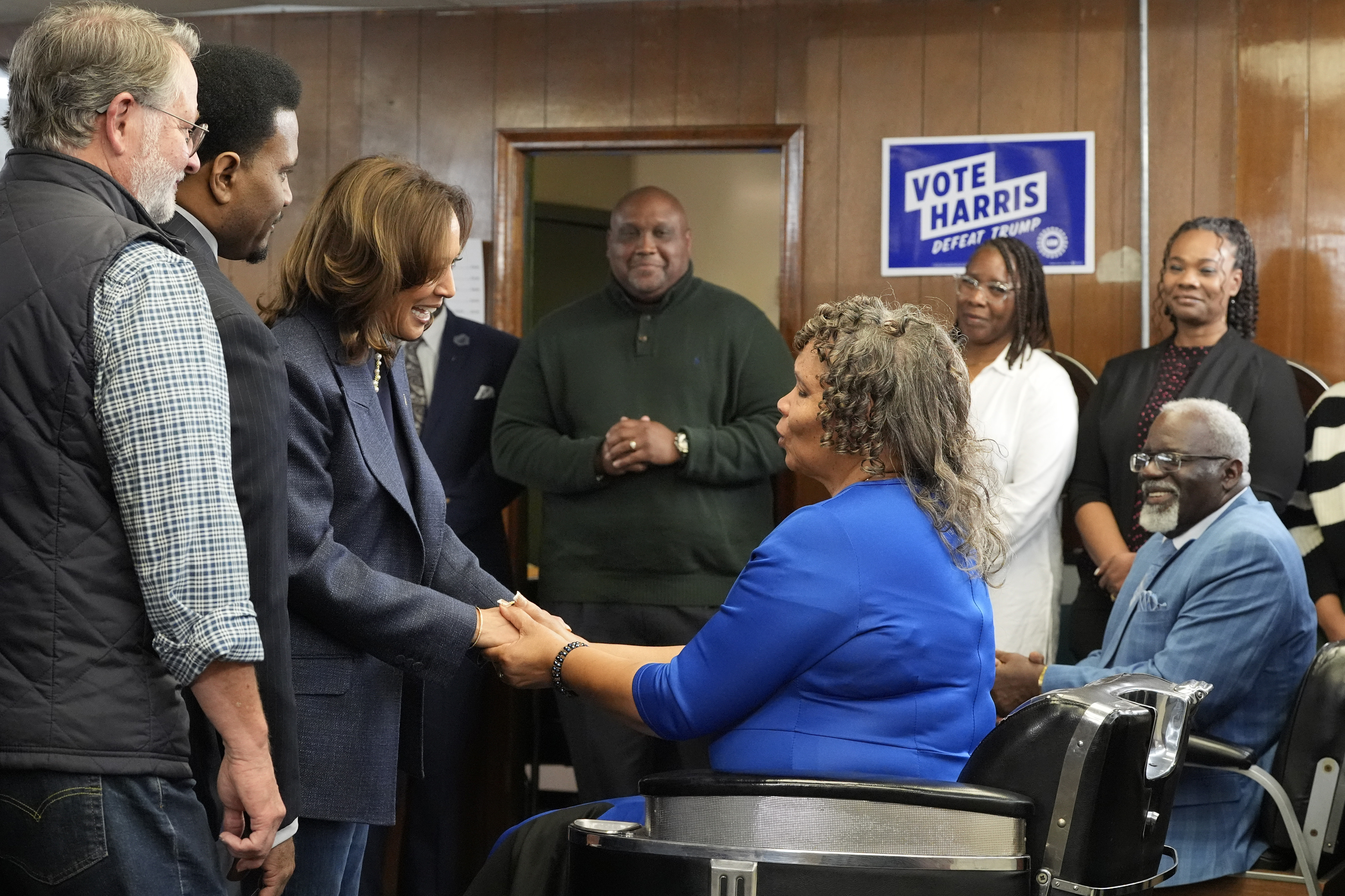 Democratic presidential nominee Vice President Kamala Harris, third left, greets Martha Roland, seated center right, and Roland Elam Sr., seated right, parents of Elam's barber shop owner Roland Elam Jr., second left, as Sen. Gary Peters, D-Mich., left, and others look on before participating in a roundtable discussion with local leaders at Elam's barber shop in Pontiac, Mich., Sunday, Nov. 3, 2024. (AP Photo/Jacquelyn Martin)