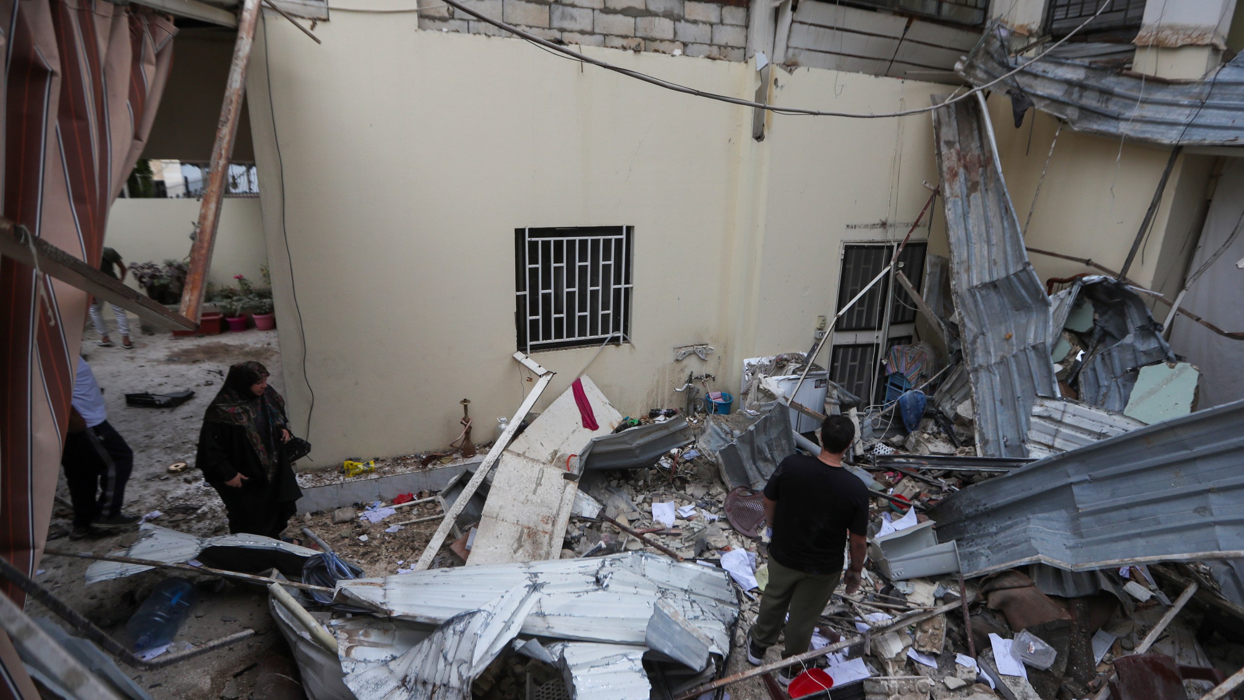 People inspect a destroyed building hit in an Israeli airstrike, in the southern port city of Sidon, Lebanon, Sunday, Nov. 3, 2024. (AP Photo/Mohammed Zaatari)