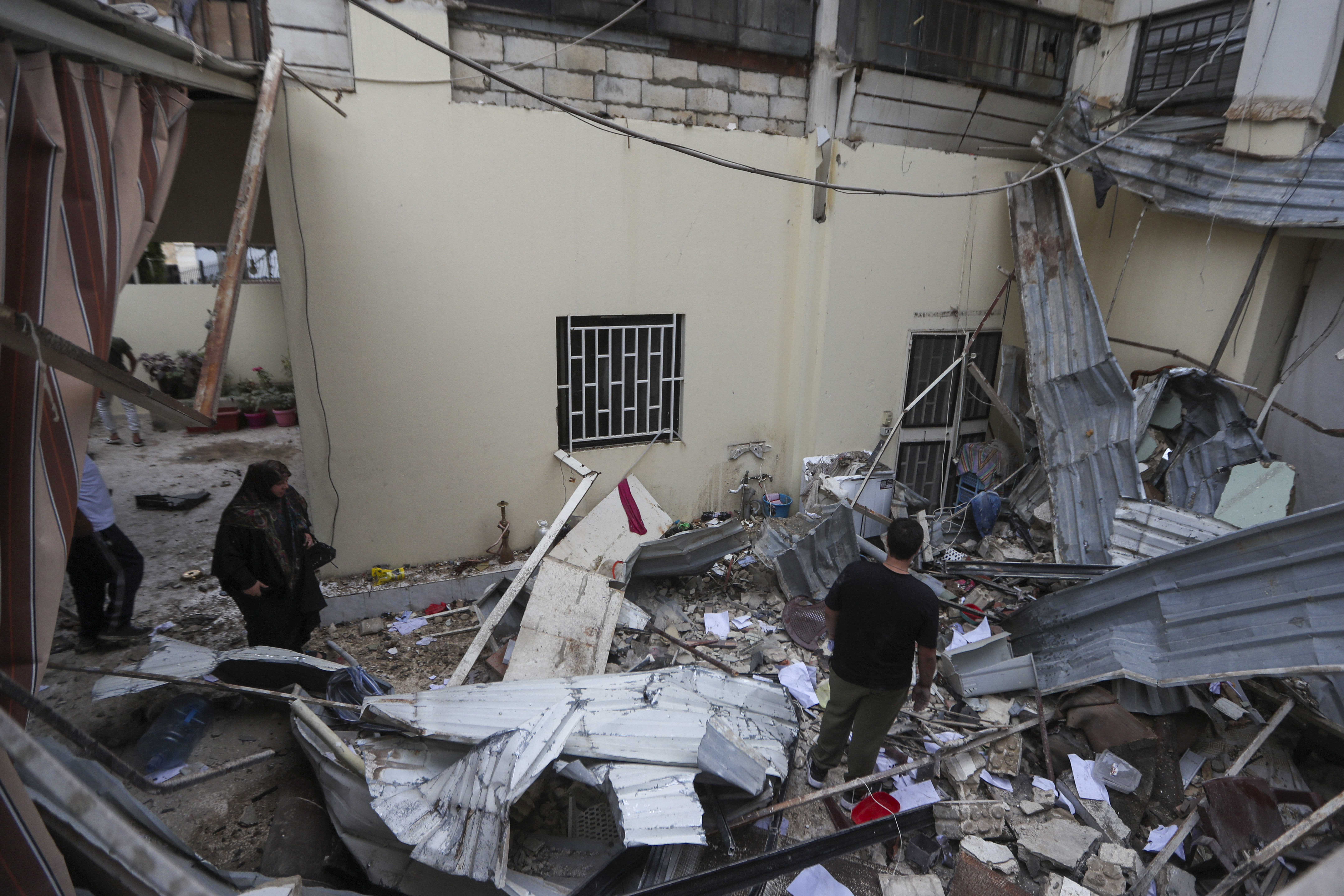 People inspect a destroyed building hit in an Israeli airstrike, in the southern port city of Sidon, Lebanon, Sunday, Nov. 3, 2024. (AP Photo/Mohammed Zaatari)