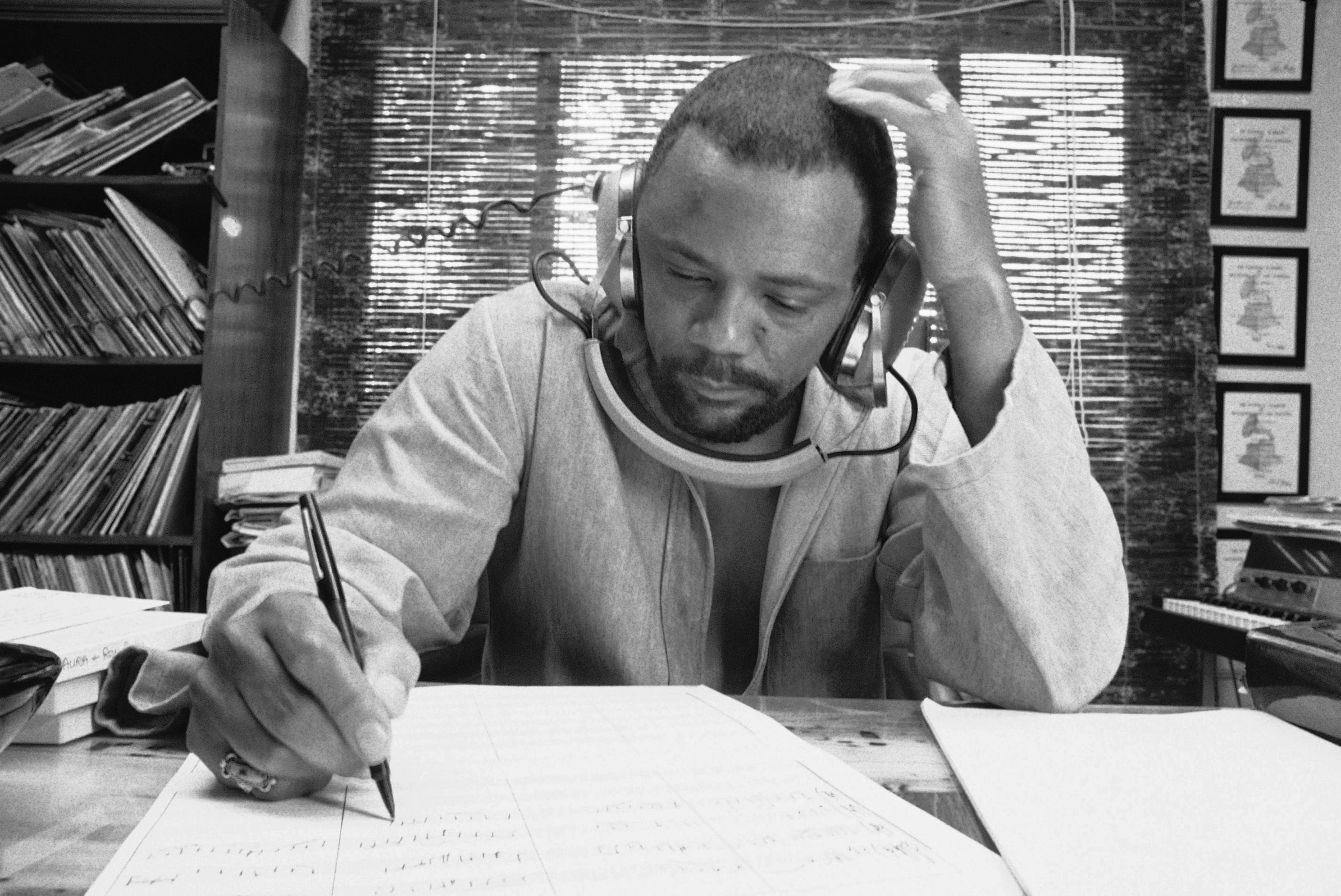 FILE - Composer Quincy Jones at his home studio in October 1974 writing music, listening to a recording on his headphones. (AP Photo/George Brich, File)