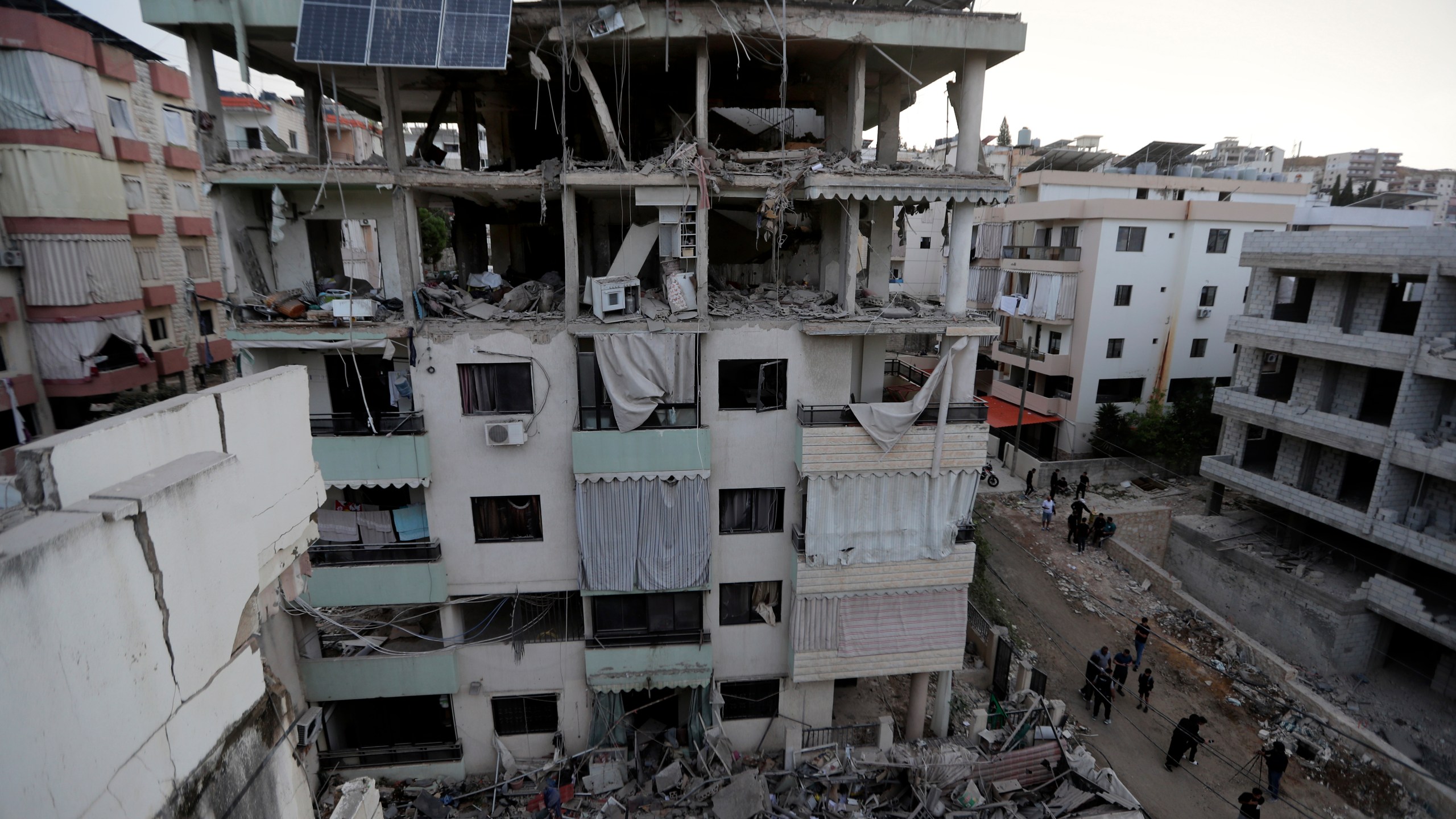 People walk past a destroyed building hit in an Israeli airstrike, in the southern port city of Sidon, Lebanon, Sunday, Nov. 3, 2024. (AP Photo/Mohammed Zaatari)