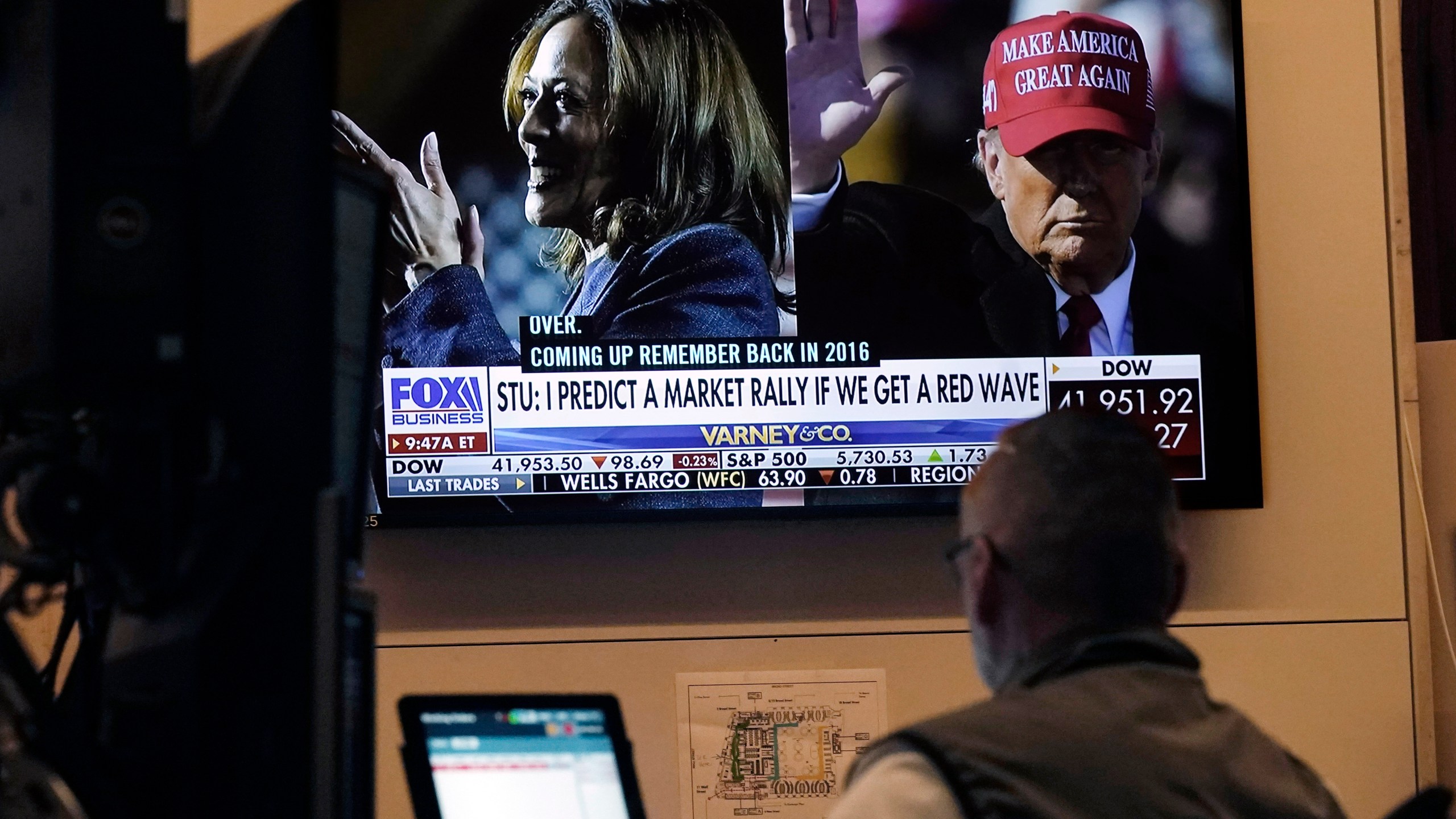 A screen on the floor of the New York Stock Exchange, Monday, Nov. 4, 2024 shows a broadcast talking about Kamala Harris and Donald Trump. (AP Photo/Richard Drew)