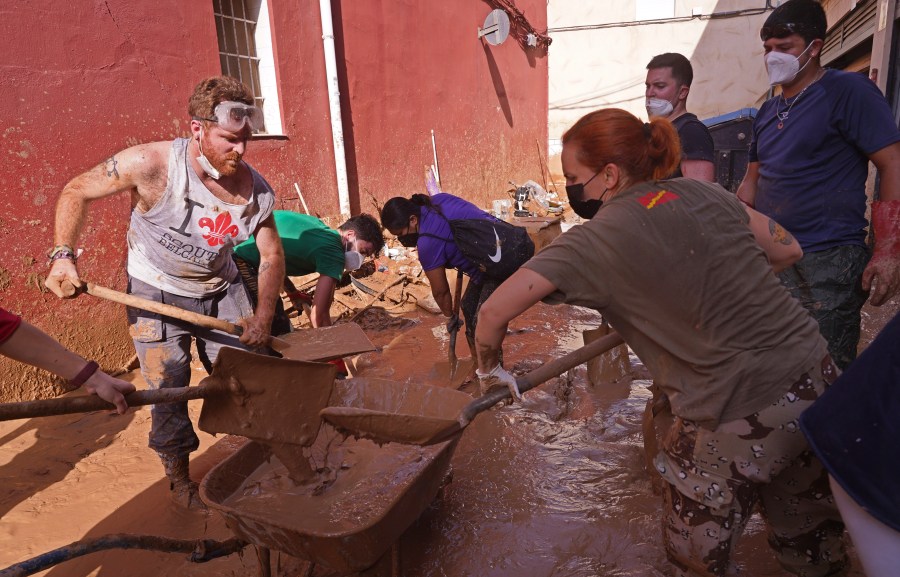 People shovel up mud after floods in Catarroja on the outskirts of Valencia, Spain, Tuesday, Nov. 5, 2024. (AP Photo/Alberto Saiz)