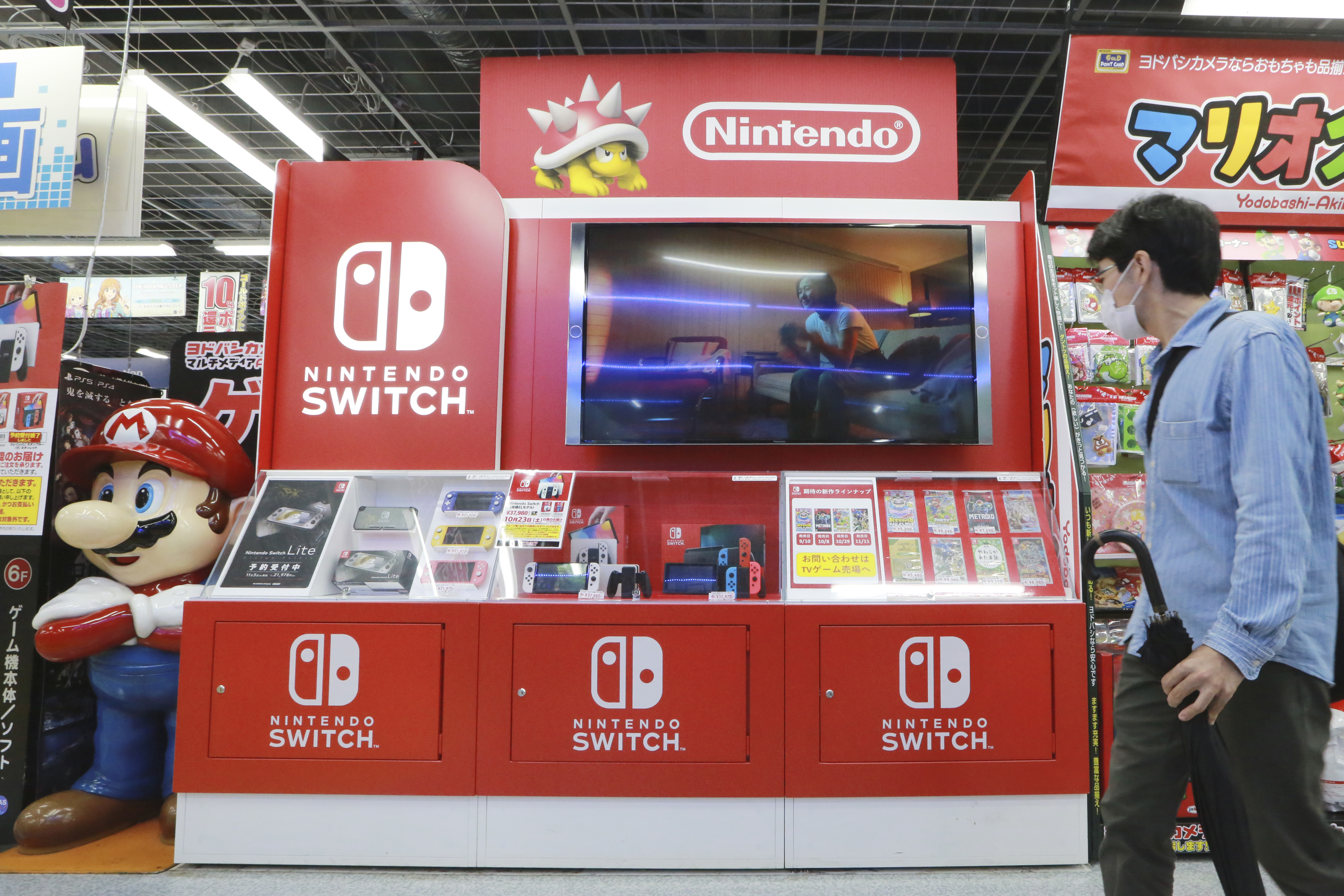 FILE - A man walks by Switch from Nintendo at an electronics retail chain store in Tokyo, on Oct. 13, 2021. (AP Photo/Koji Sasahara, File)