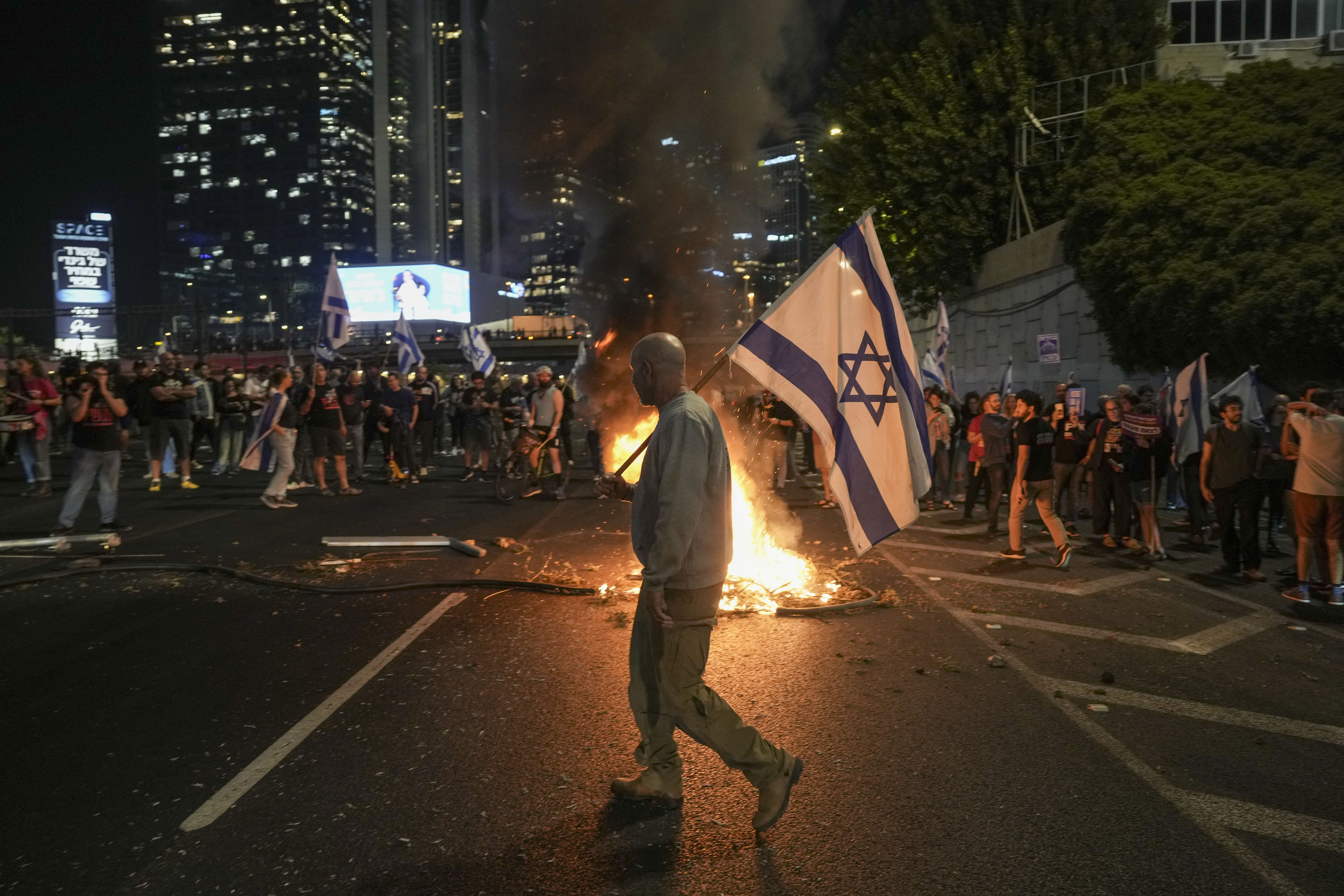 Israelis light a bonfire during a protest after Prime Minister Benjamin Netanyahu has dismissed his popular defense minister Yoav Gallant, in Tel Aviv, Israel, Tuesday, Nov. 5, 2024. (AP Photo/Oded Balilty)