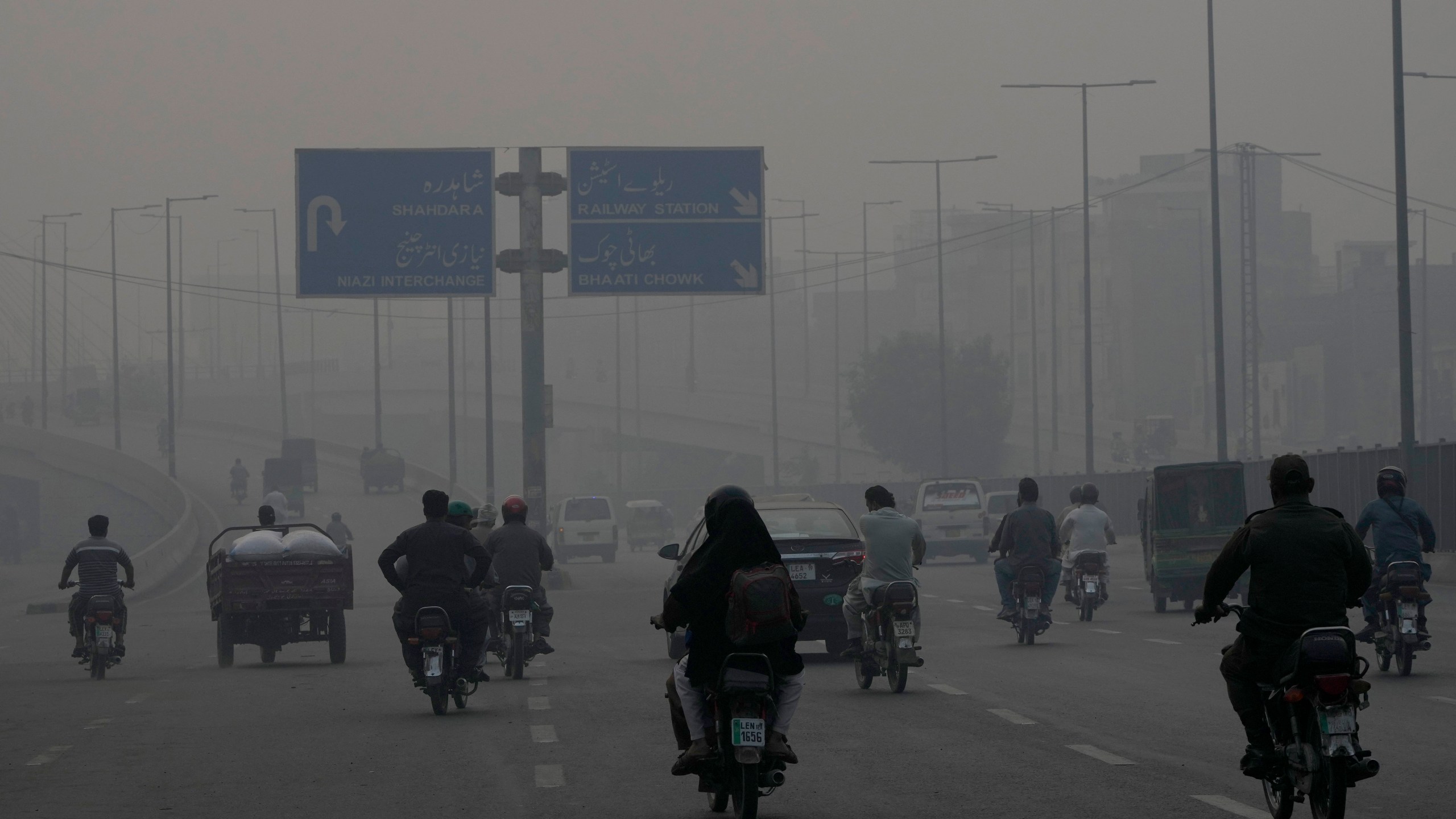 Motorcyclists drive on a highway as smog envelops the areas of Lahore, Pakistan, Wednesday, Nov. 6, 2024. (AP Photo/K.M. Chaudary)