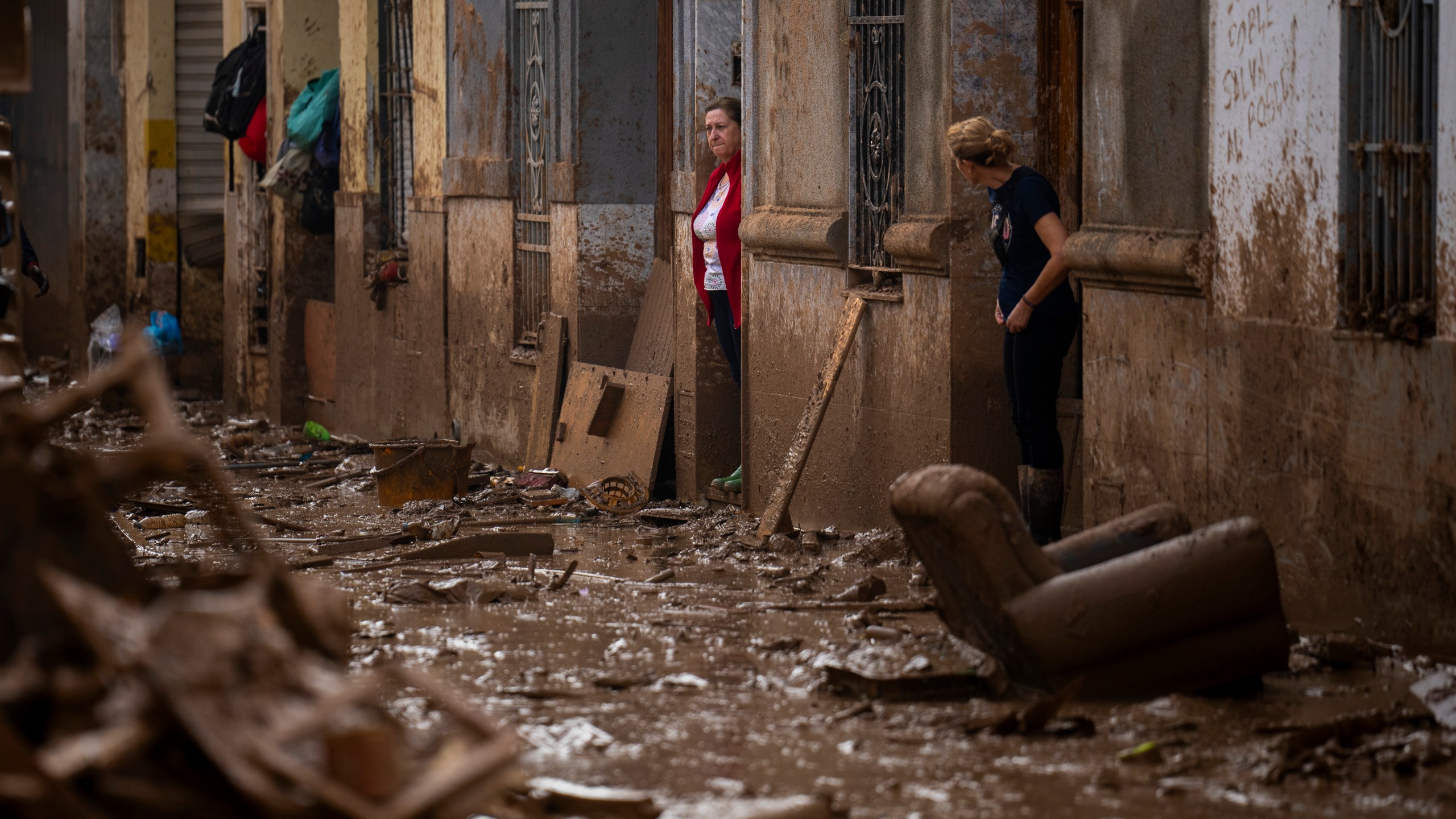 Women stand at the entrance of their houses affected by flooding in Masanasa, Valencia, Spain, Wednesday, Nov. 6, 2024. (AP Photo/Emilio Morenatti)