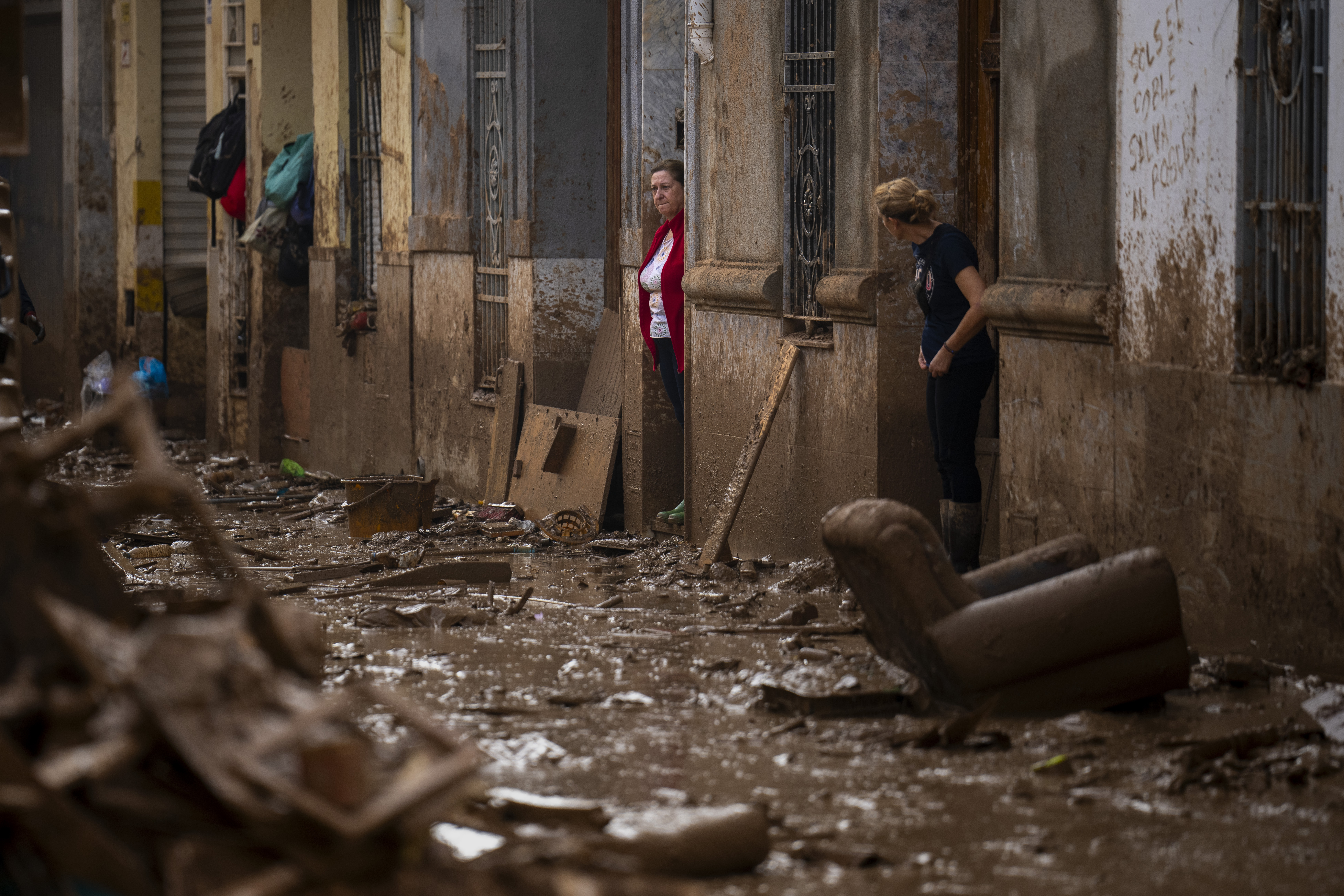 Women stand at the entrance of their houses affected by flooding in Masanasa, Valencia, Spain, Wednesday, Nov. 6, 2024. (AP Photo/Emilio Morenatti)