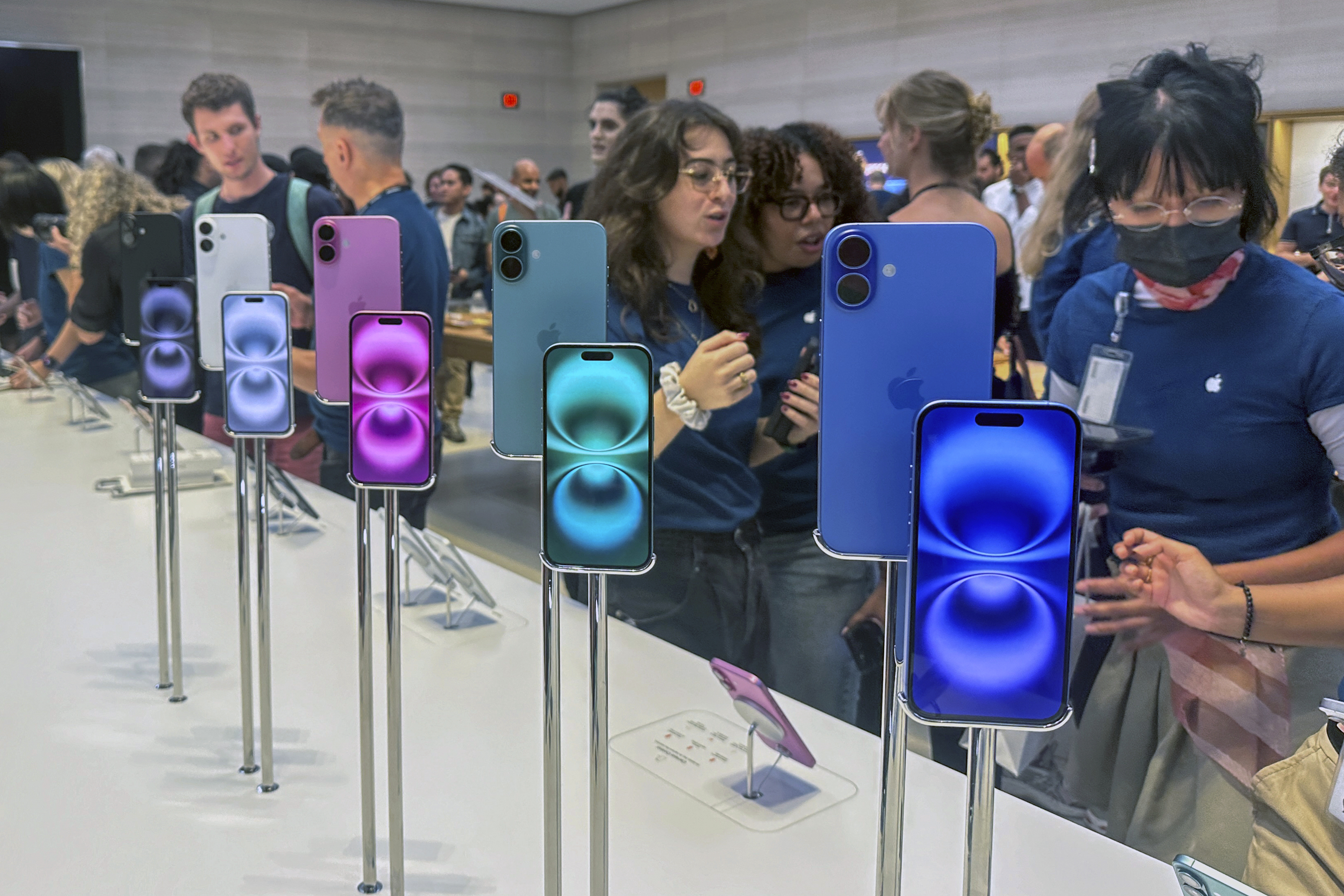 FILE - People gather near a display of iPhone 16's at the Apple Store on 5th Ave. in New York on September 20, 2024.(AP Photo/Ted Shaffrey, File)