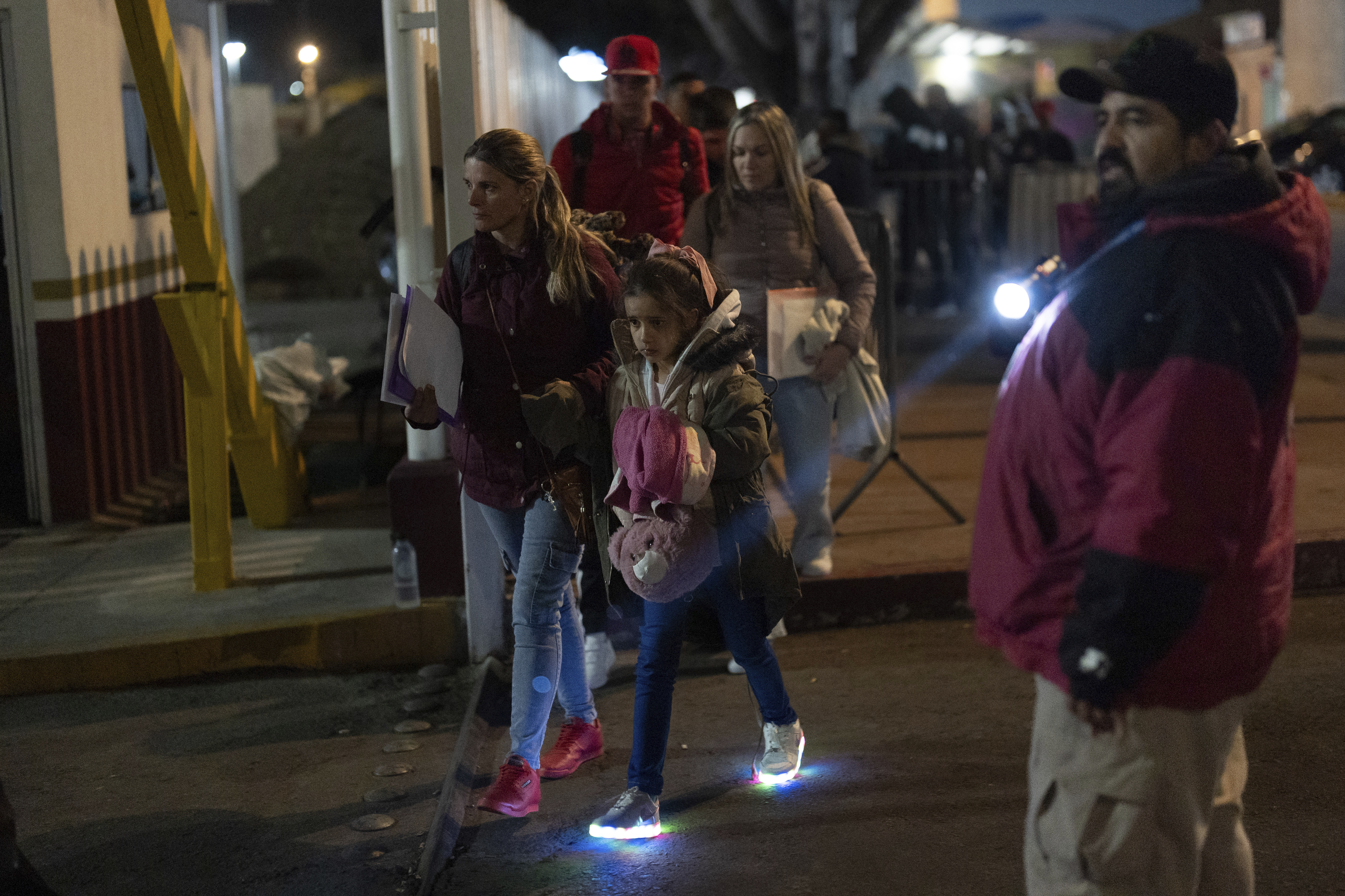 FILE - Migrants from Cuba pass a Mexican customs checkpoint as they make their way across the border for their appointments to legally apply for asylum in the United States, on Nov. 5, 2024, in Tijuana, Mexico. (AP Photo/Gregory Bull, File)