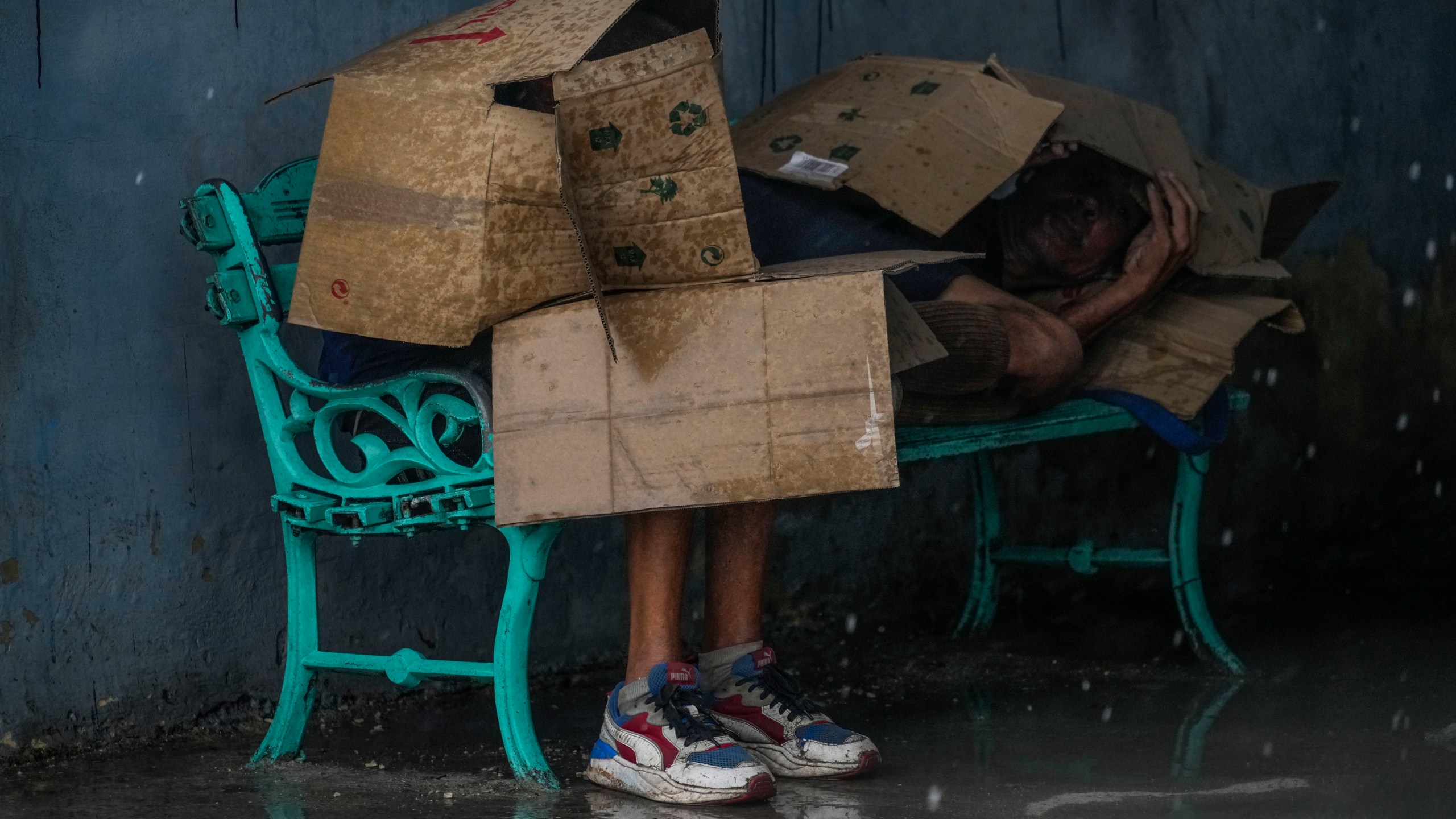 People at a bus stop shield themselves with cardboard amid wind and rain during the passage of Hurricane Rafael in Havana, Cuba, Wednesday, Nov. 6, 2024. (AP Photo/Ramon Espinosa)