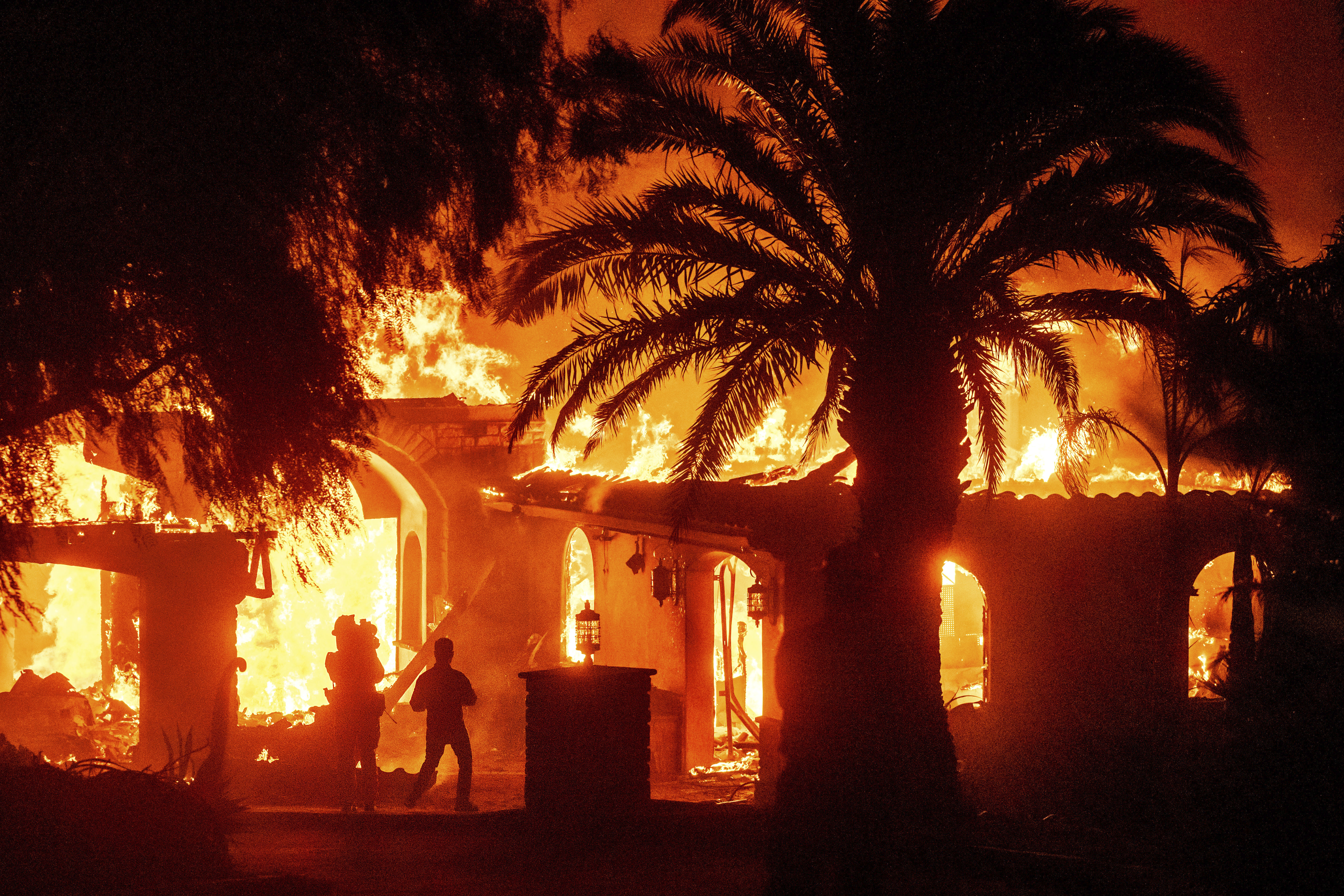 Television reporters film as flames from the Mountain Fire consume a home in Camarillo, Calif., on Wednesday, Nov. 6, 2024. (AP Photo/Noah Berger)