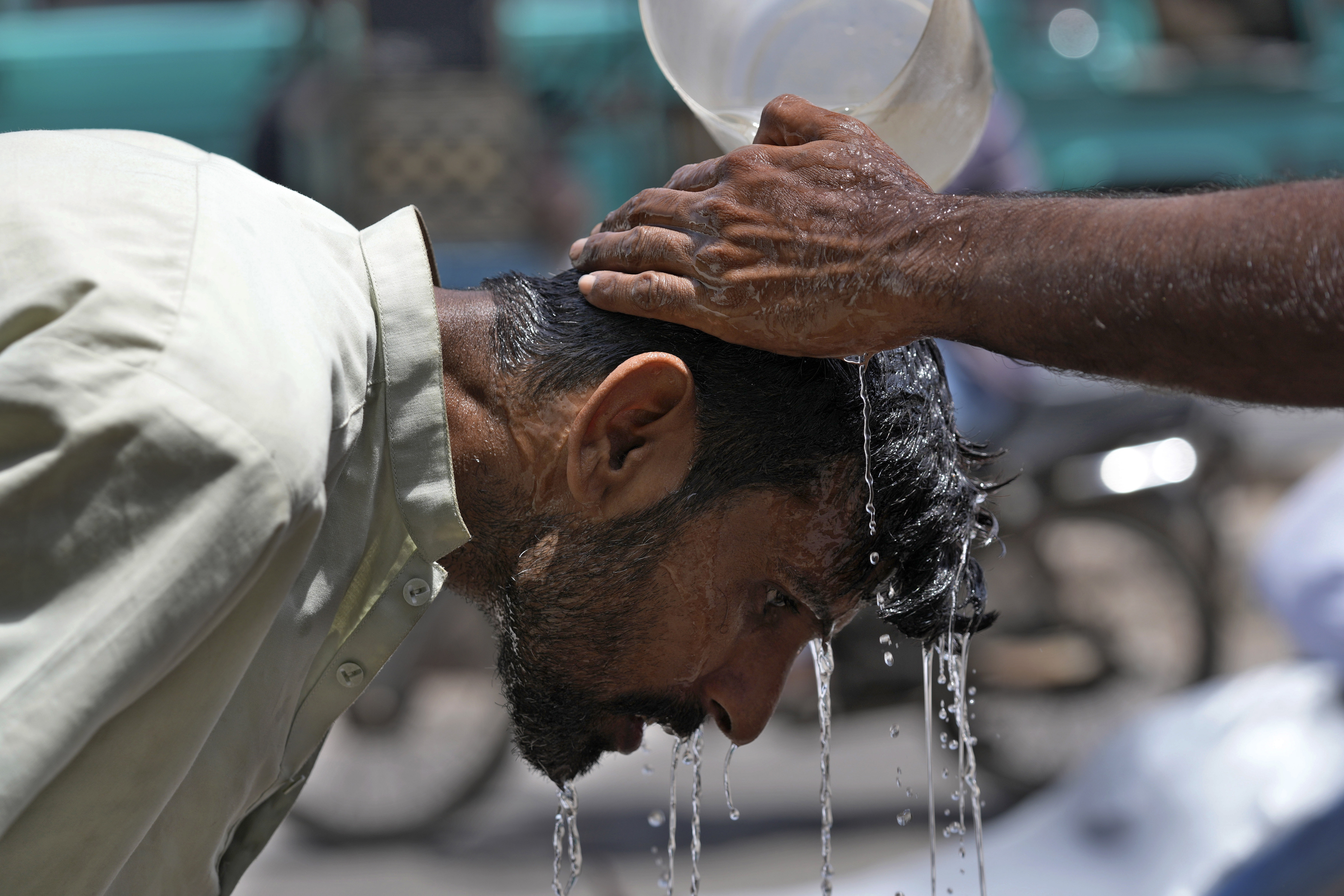 FILE - A volunteer pours water to cool a man off during a hot day in Karachi, Pakistan, May 21, 2024. (AP Photo/Fareed Khan, File)