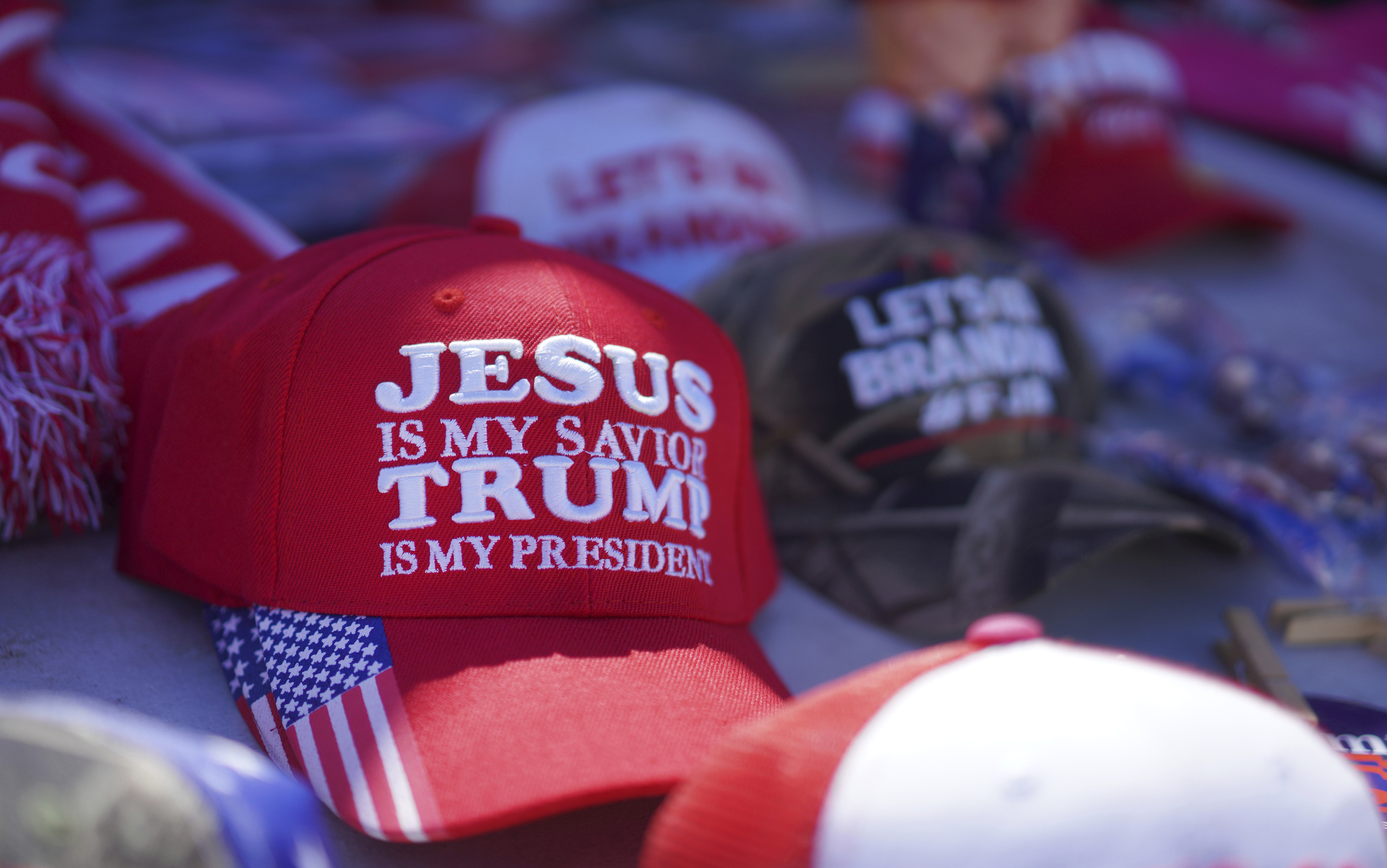 FILE - Hats reading a variety of slogans including, "Jesus is my savior, Trump is my president," are sold at a campaign rally for former President Donald Trump in Vandalia, Ohio, March 16, 2024. (AP Photo/Jessie Wardarski, File)