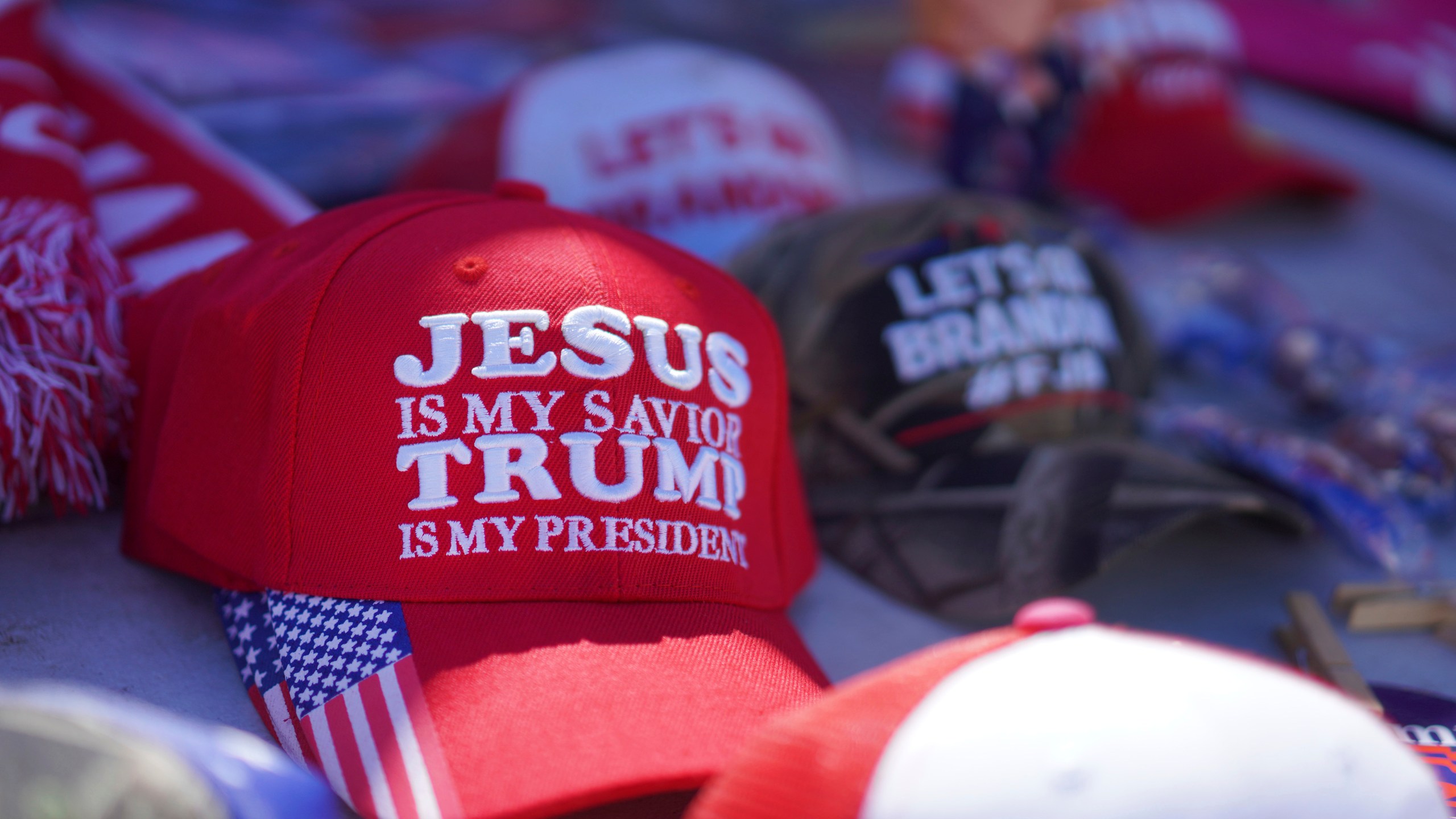 FILE - Hats reading a variety of slogans including, "Jesus is my savior, Trump is my president," are sold at a campaign rally for former President Donald Trump in Vandalia, Ohio, March 16, 2024. (AP Photo/Jessie Wardarski, File)