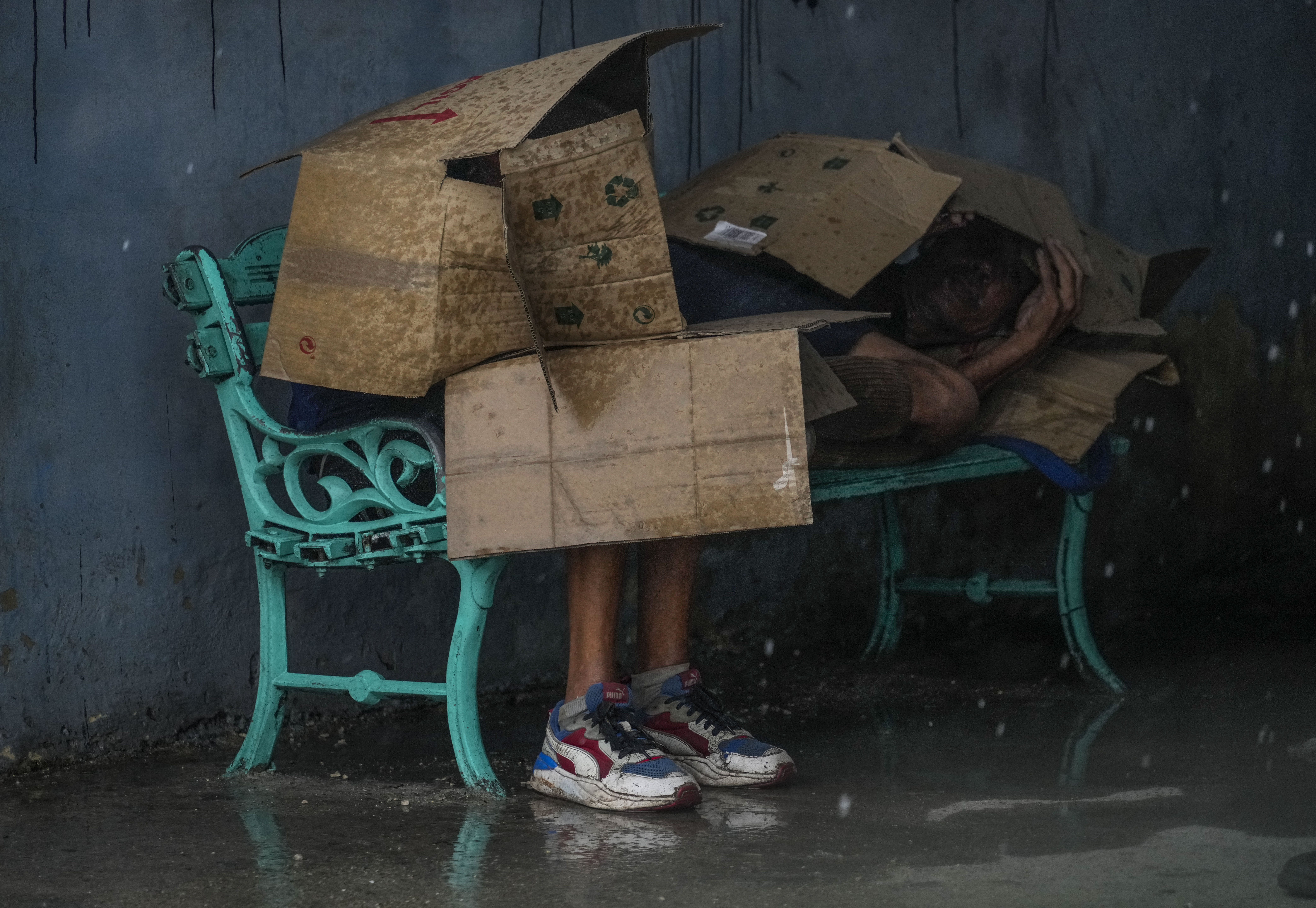 People at a bus stop shield themselves with cardboard amid wind and rain during the passage of Hurricane Rafael in Havana, Cuba, Wednesday, Nov. 6, 2024. (AP Photo/Ramon Espinosa)