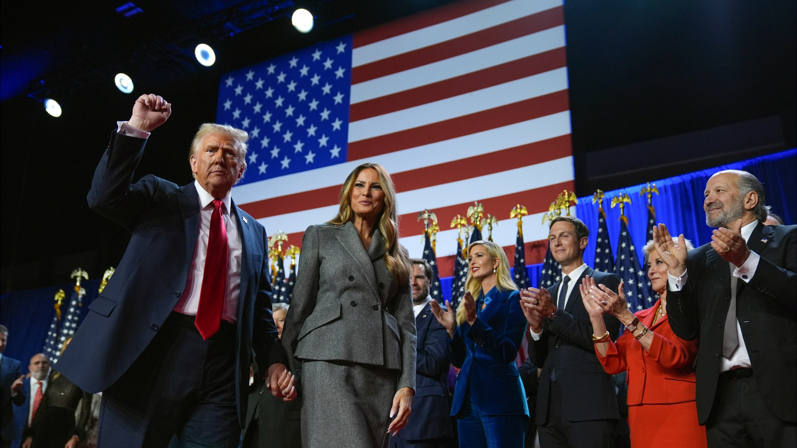 Republican presidential nominee former President Donald Trump gestures as he walks with former first lady Melania Trump at an election night watch party at the Palm Beach Convention Center, Wednesday, Nov. 6, 2024, in West Palm Beach, Fla. (AP Photo/Evan Vucci)