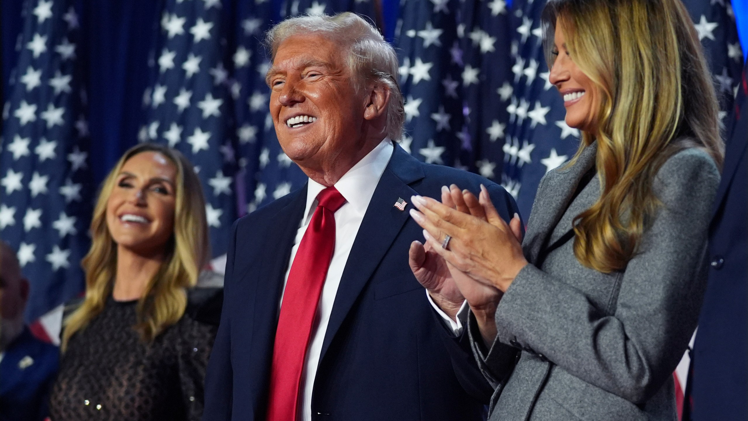 Republican presidential nominee former President Donald Trump stands on stage with former first lady Melania Trump, as Lara Trump watches, at an election night watch party at the Palm Beach Convention Center, Wednesday, Nov. 6, 2024, in West Palm Beach, Fla. (AP Photo/Evan Vucci)