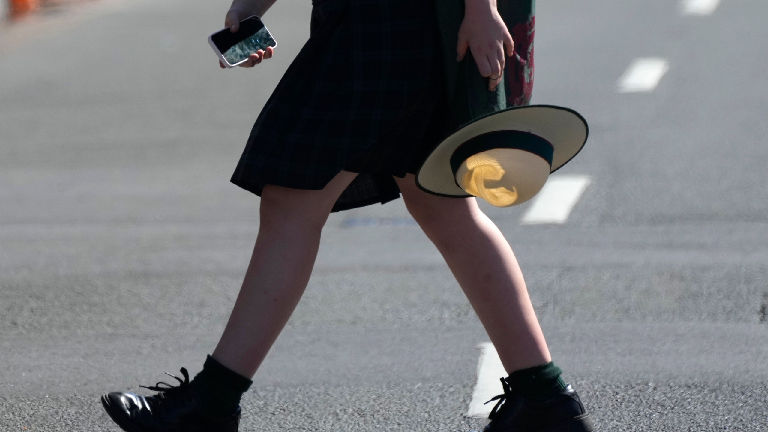 A school girl holds her phone while crossing a street in Sydney, Friday, Nov. 8, 2024. (AP Photo/Rick Rycroft)