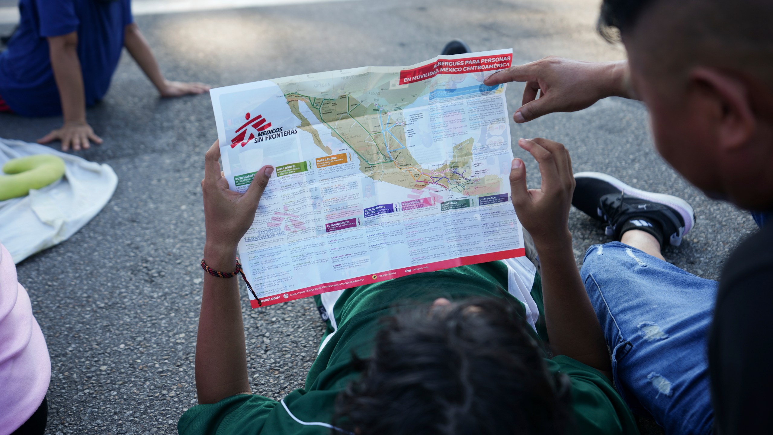 Migrants, who are part of a a caravan heading toward the country's northern border and ultimately the United States, check a map during a break, on the outskirts of Escuintla, southern Mexico, Thursday, Nov. 7, 2024. (AP Photo/Moises Castillo)