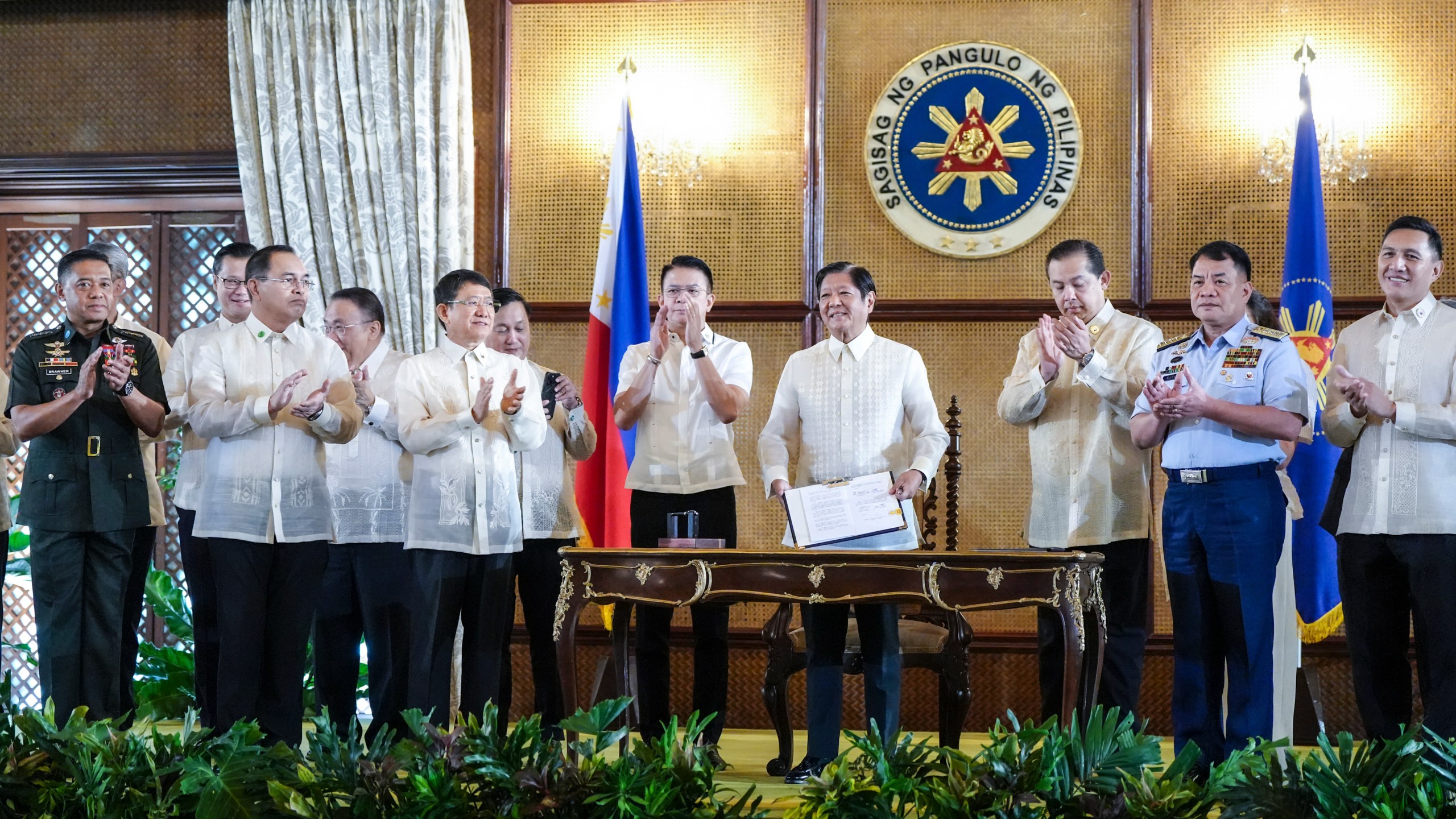 In this photo provided by the Malacanang Presidential Communications Office, Philippine President Ferdinand Marcos Jr., 4th from right, holds a document during the ceremonial signing of the Philippine Maritime Zones and Philippine Archipelagic Sea Lanes Act at the Malacanang presidential palace in Manila, Philippines on Friday, Nov. 8, 2024. (Malacanang Presidential Communications Office via AP)