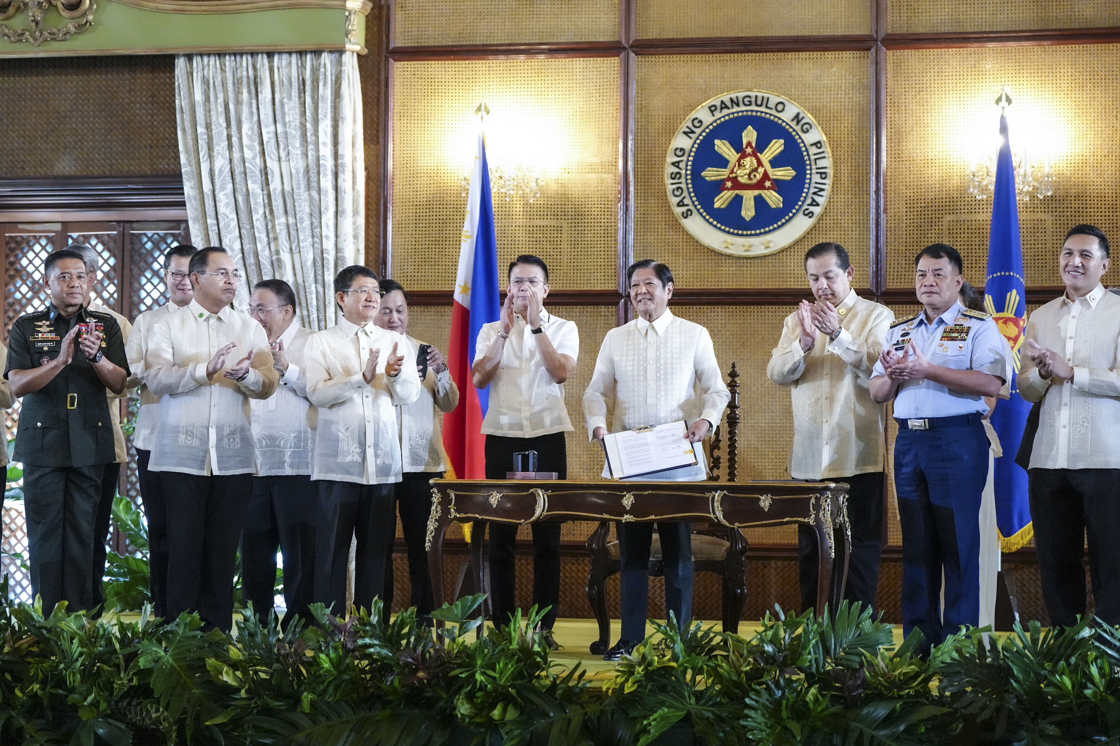 In this photo provided by the Malacanang Presidential Communications Office, Philippine President Ferdinand Marcos Jr., 4th from right, holds a document during the ceremonial signing of the Philippine Maritime Zones and Philippine Archipelagic Sea Lanes Act at the Malacanang presidential palace in Manila, Philippines on Friday, Nov. 8, 2024. (Malacanang Presidential Communications Office via AP)