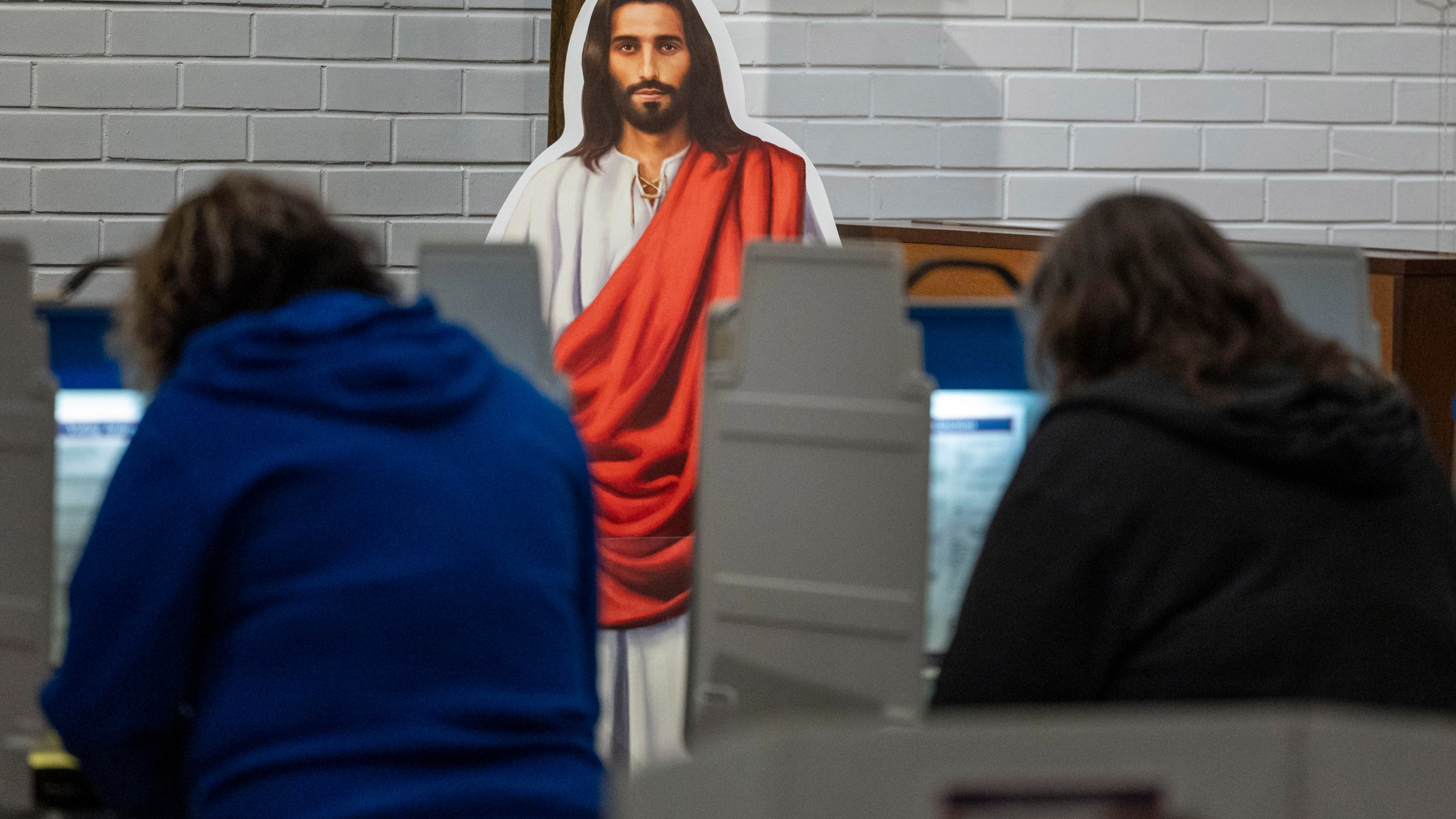 A cutout of Jesus watches over voters at the voting station at Redeemer Lutheran Church on Election Day, Tuesday, Nov. 5, 2024, in Lincoln, Neb. (Kenneth Ferriera/Lincoln Journal Star via AP)