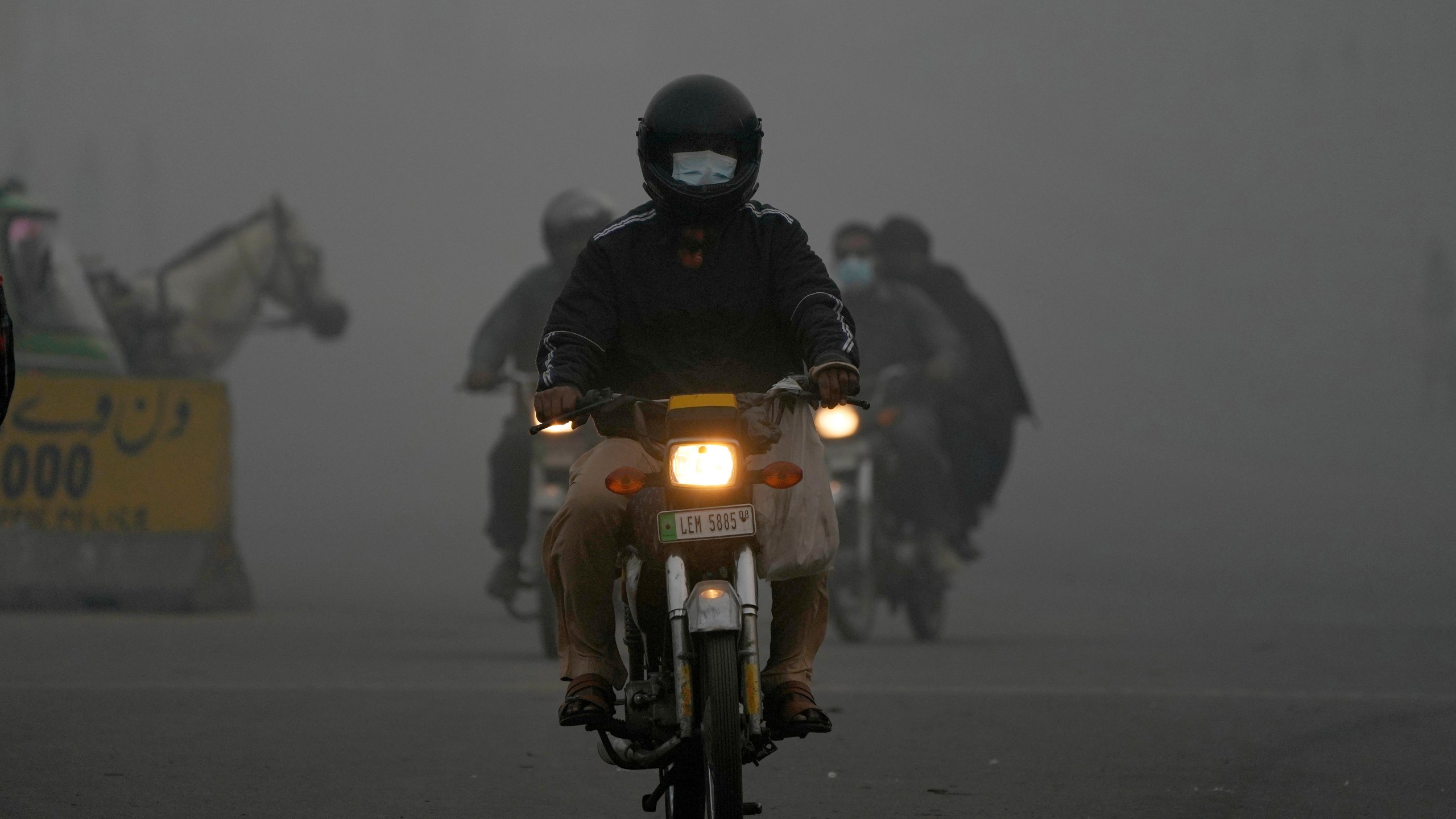 Motorcyclists move with headlights in the morning due to smog in Lahore, Pakistan, Friday, Nov. 8, 2024. (AP Photo/K.M. Chaudary)