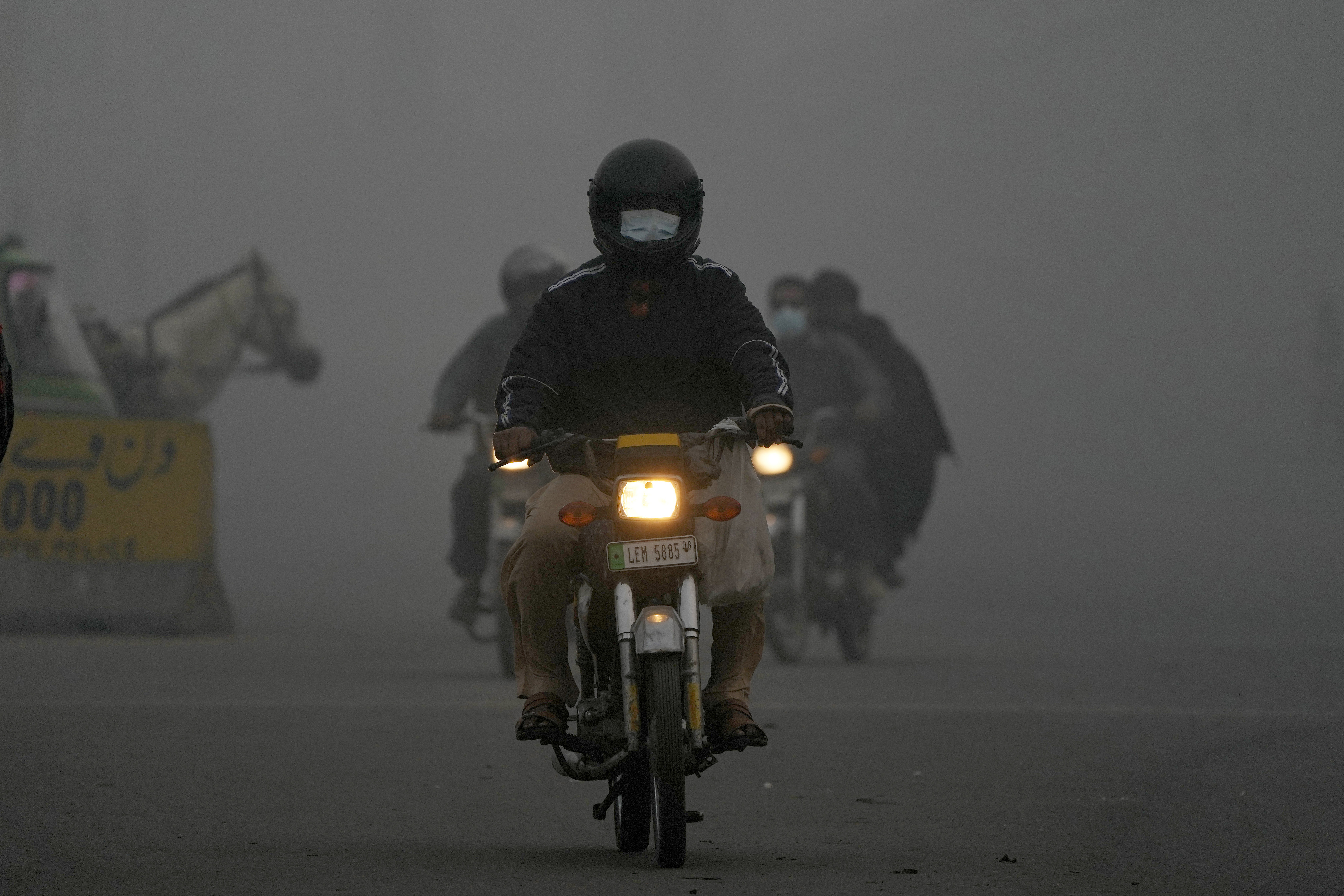 Motorcyclists move with headlights in the morning due to smog in Lahore, Pakistan, Friday, Nov. 8, 2024. (AP Photo/K.M. Chaudary)