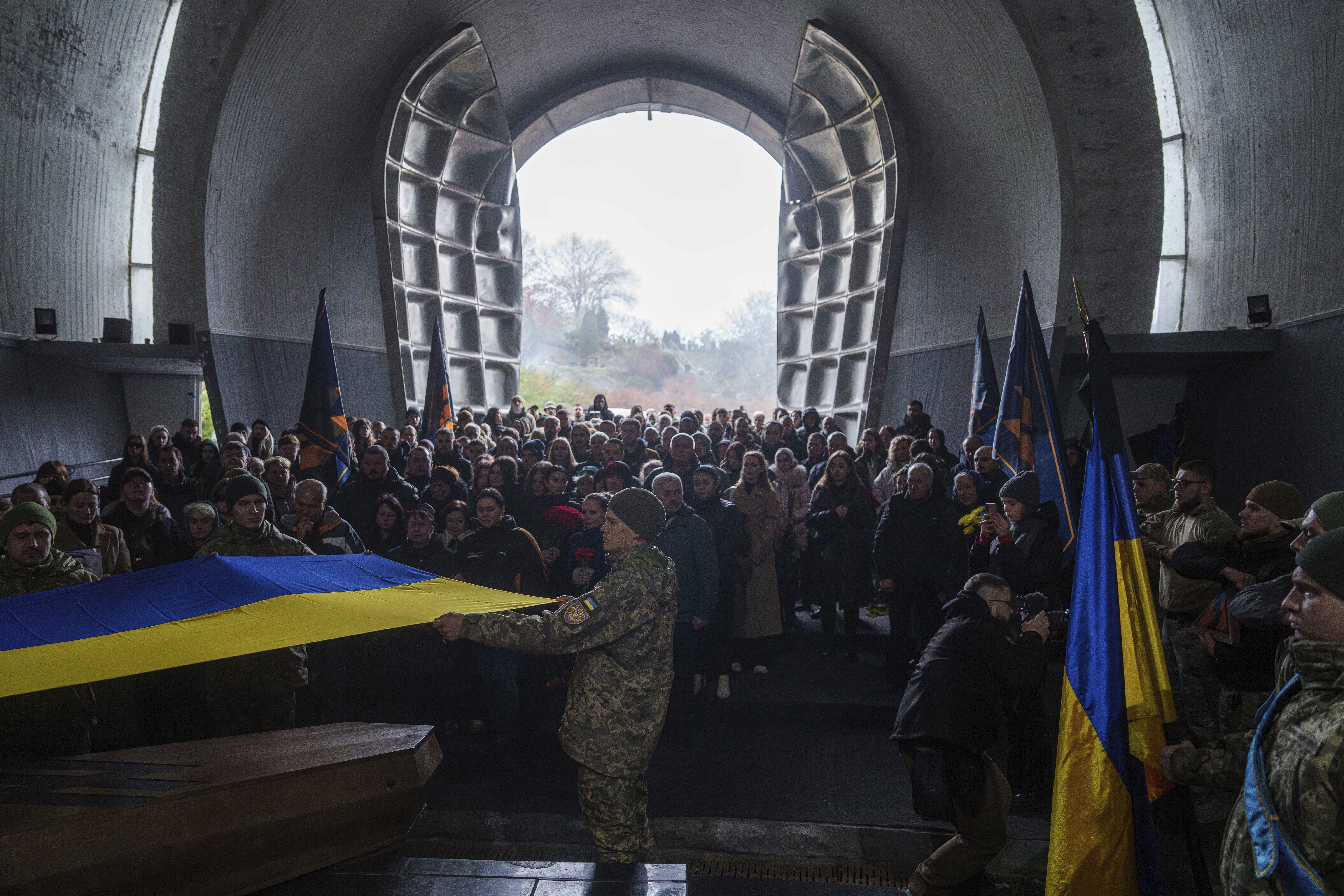 Honour Guard hold the national flag above the coffin of fallen Ukrainian serviceman of 3rd assault brigade Danylo Liashkevych, known as "Berserk", who was killed together with his girlfriend Valentyna Nagorna, known as "Valkiria", during the funeral ceremony at a crematorium in Kyiv, Ukraine, Friday Nov. 8, 2024. (AP Photo/Evgeniy Maloletka)