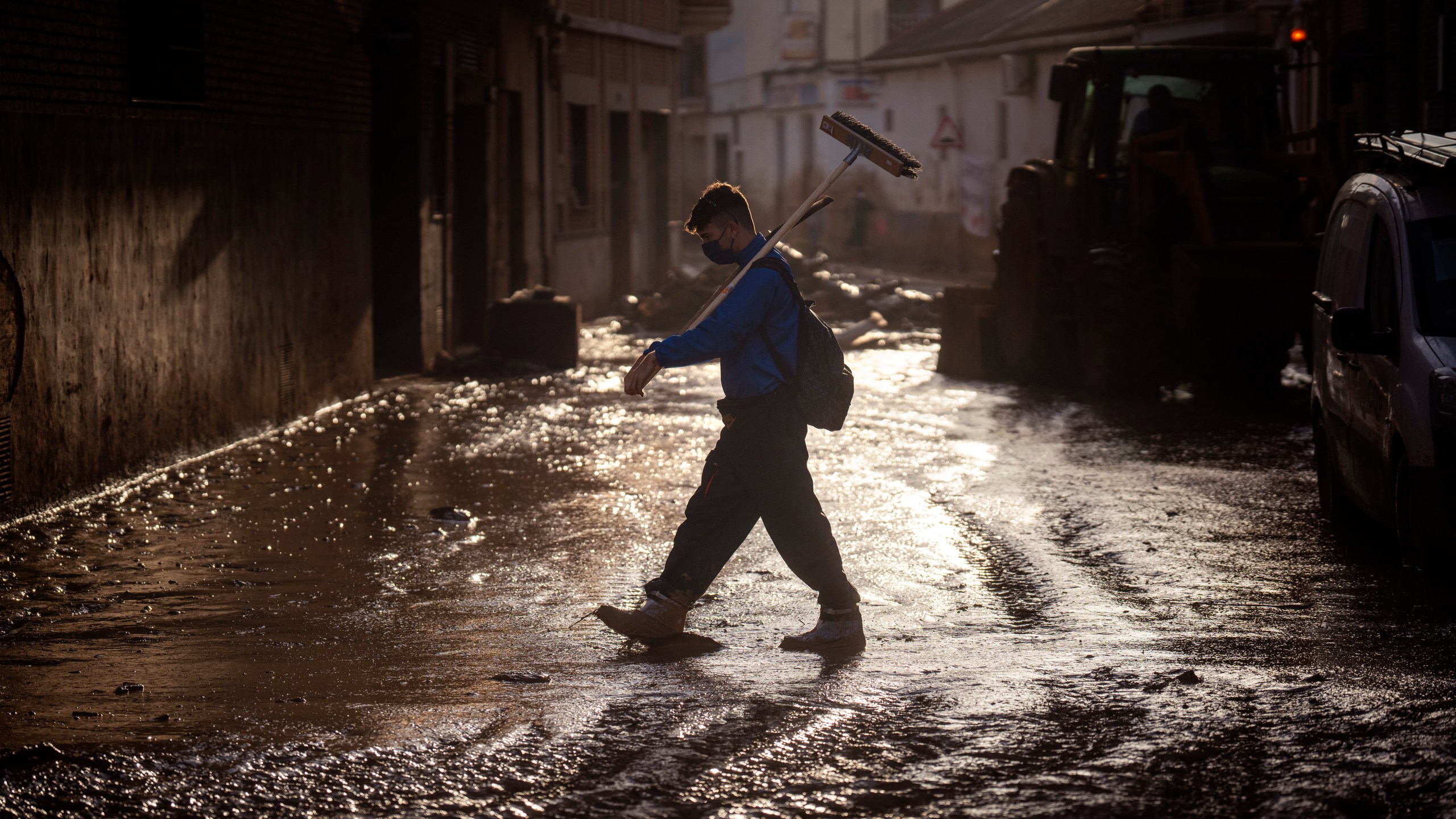 A volunteer walks with a broom over a muddy street in Massanassa, Valencia, Spain, Friday, Nov. 8, 2024. (AP Photo/Emilio Morenatti)