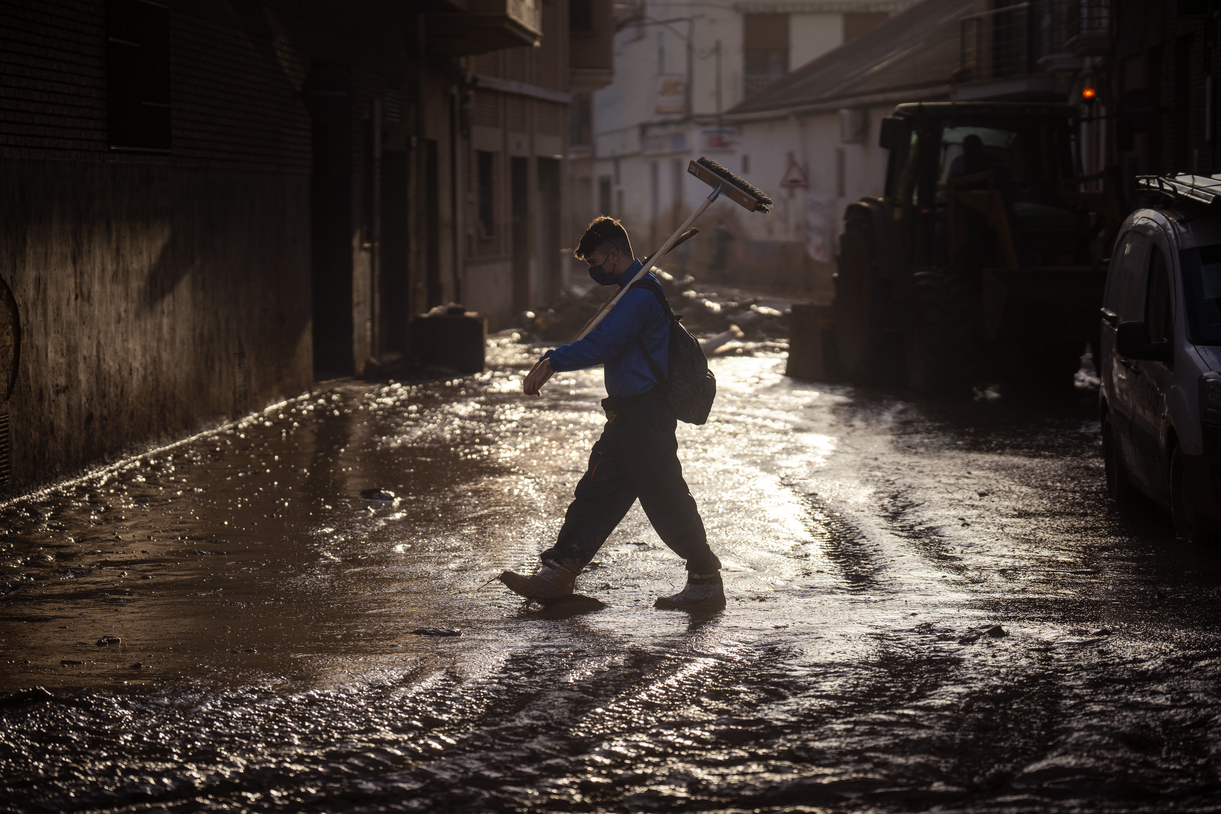 A volunteer walks with a broom over a muddy street in Massanassa, Valencia, Spain, Friday, Nov. 8, 2024. (AP Photo/Emilio Morenatti)