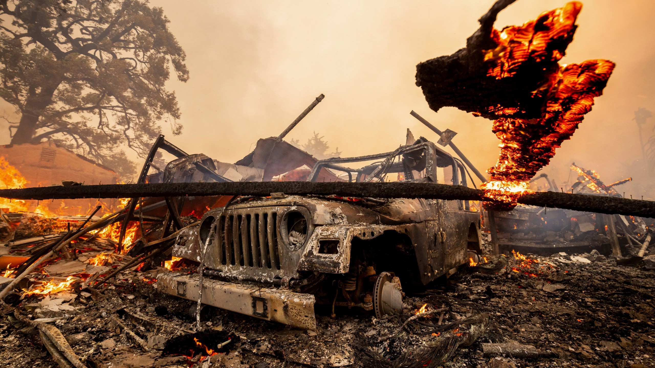 A burned vehicle sits among a destroyed home in the Mountain Fire, Nov. 6, 2024, near Camarillo, Calif. (AP Photo/Ethan Swope)