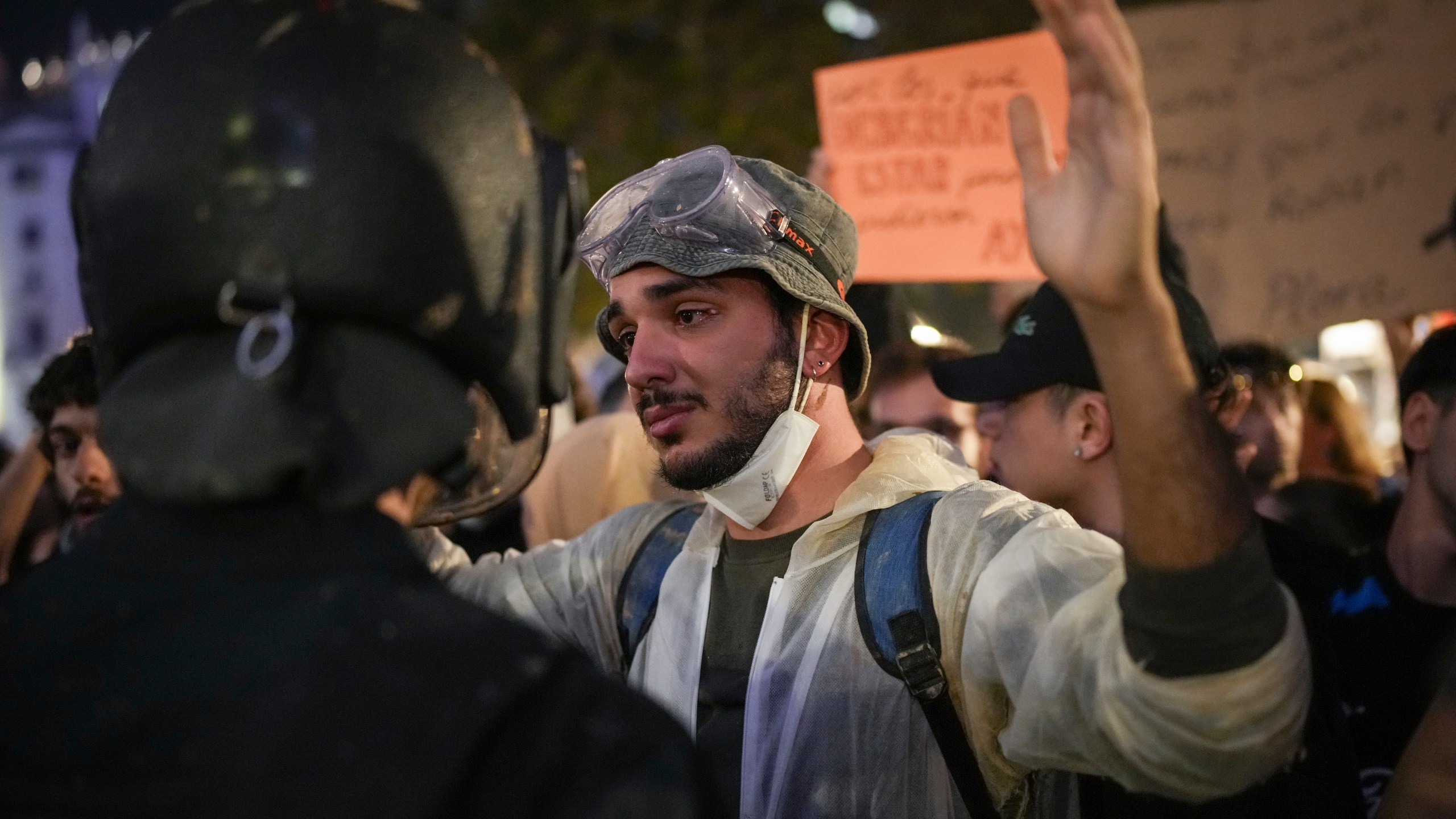 A demonstrator holds his hands up in front of riot police during a protest organized by social and civic groups, denouncing the handling of recent flooding under the slogan "Mazón, Resign," aimed at the president of the regional government Carlos Mazon, in Valencia, Spain, Saturday, Nov. 9, 2024. (AP Photo/Emilio Morenatti)