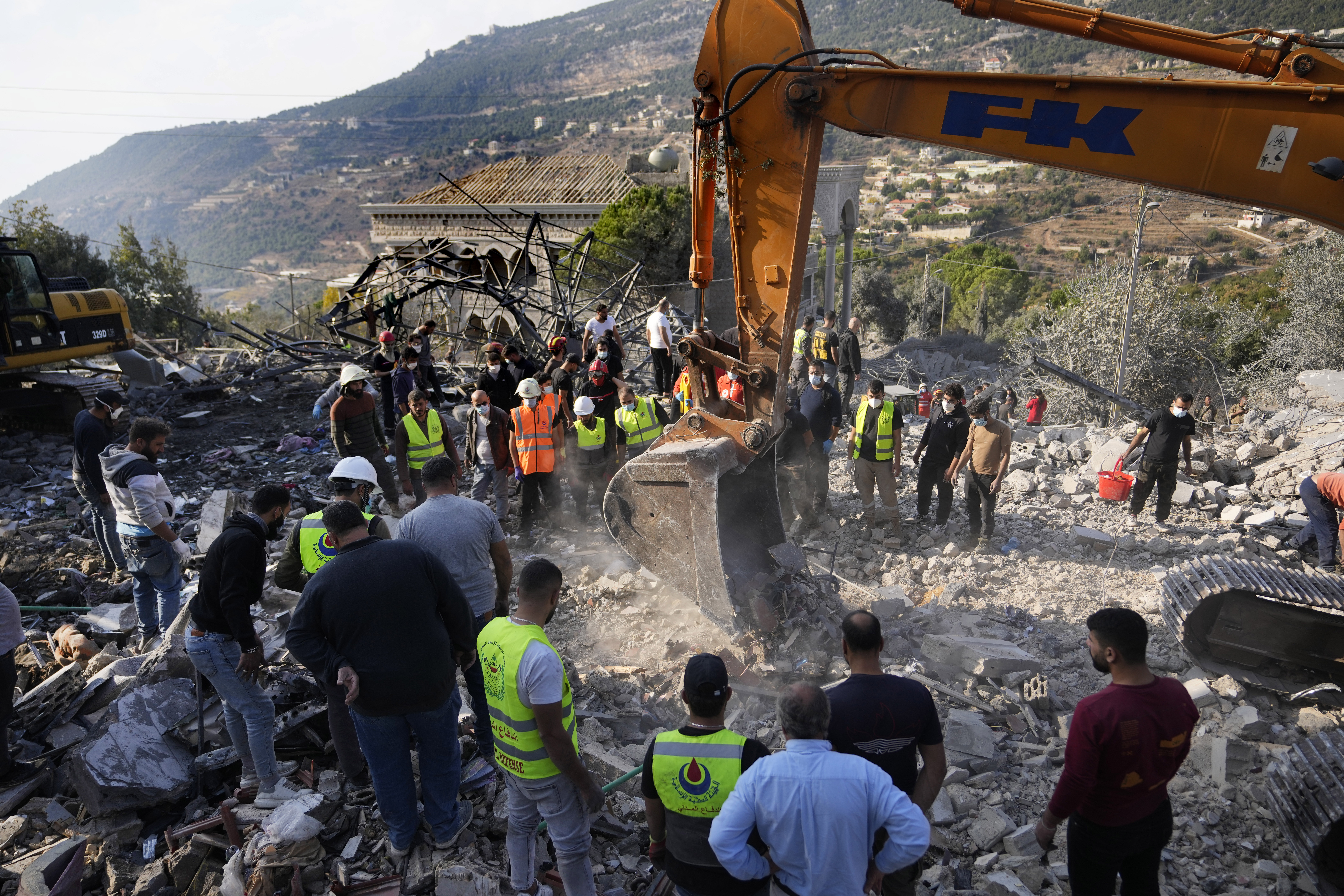 Rescue workers use an excavator to remove the rubble of a destroyed house hit in an Israeli airstrike, as they search for victims in Aalmat village, northern Lebanon, Sunday, Nov. 10, 2024. (AP Photo/Hassan Ammar)